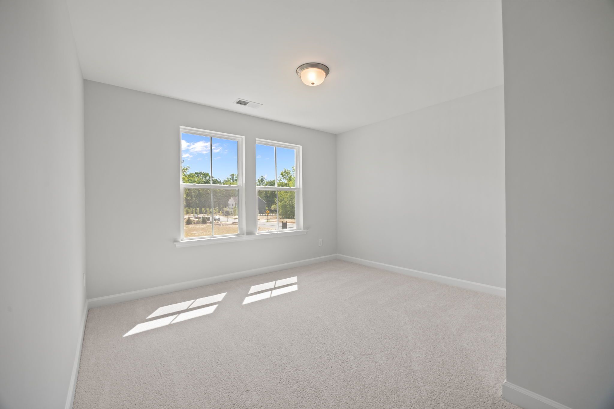 Spacious, carpeted bedroom in The Ashport B floor plan featuring neutral paint and natural light from large windows.