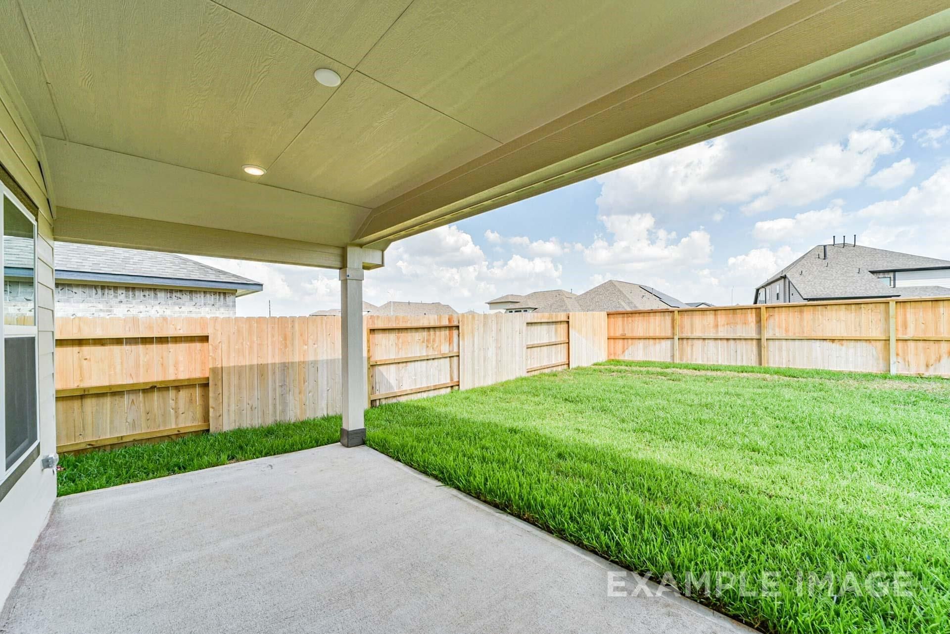Covered back patio with a private fenced backyard at The Riviera A floor plan in Emberly, Beasley, Texas.