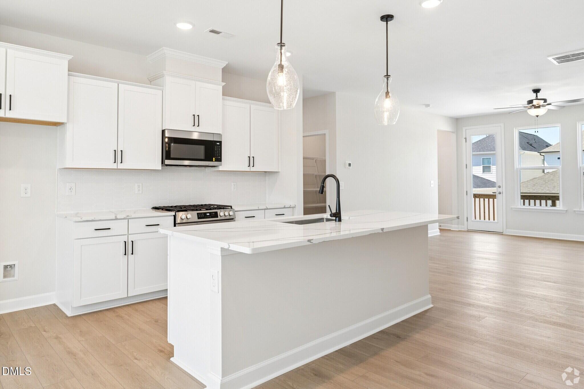 Bright white kitchen with island, pendant lights, and quartz counters in Davidson Homes The Mitchell floor plan, Knightdale, NC