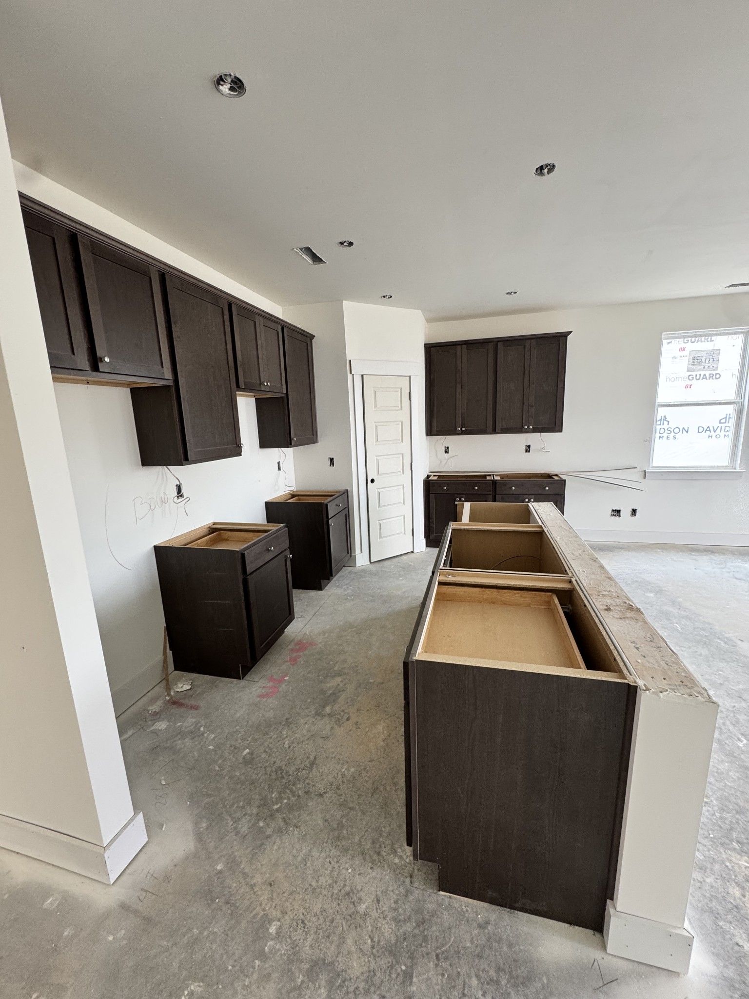 Under-construction kitchen with dark wood cabinets, large island, and recessed lighting in Davidson Homes Cottonwood E, Gallatin TN
