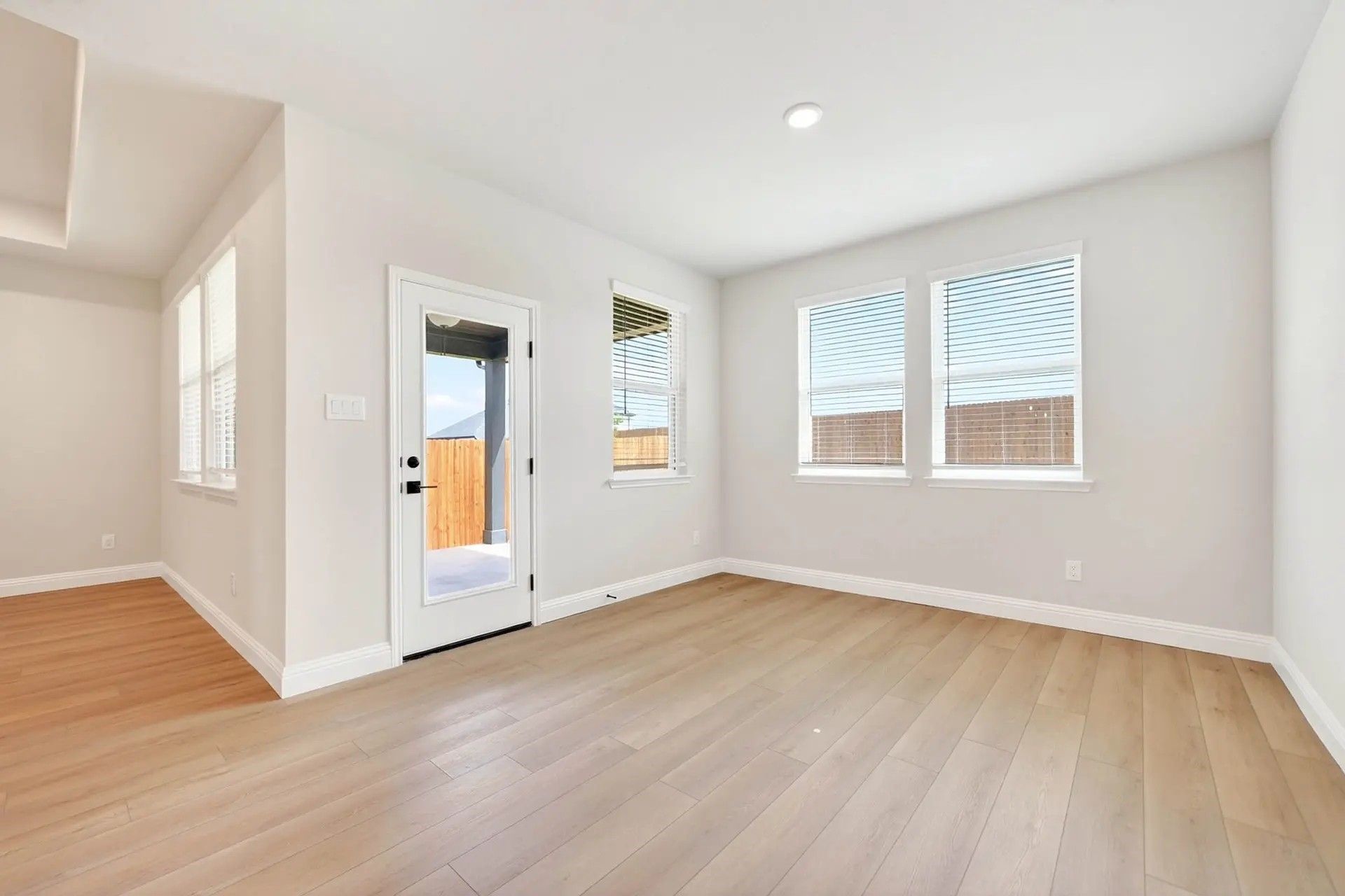 Bright living area with light wood floors and patio access in The Holly C floor plan by Davidson Homes in Heartland, TX.