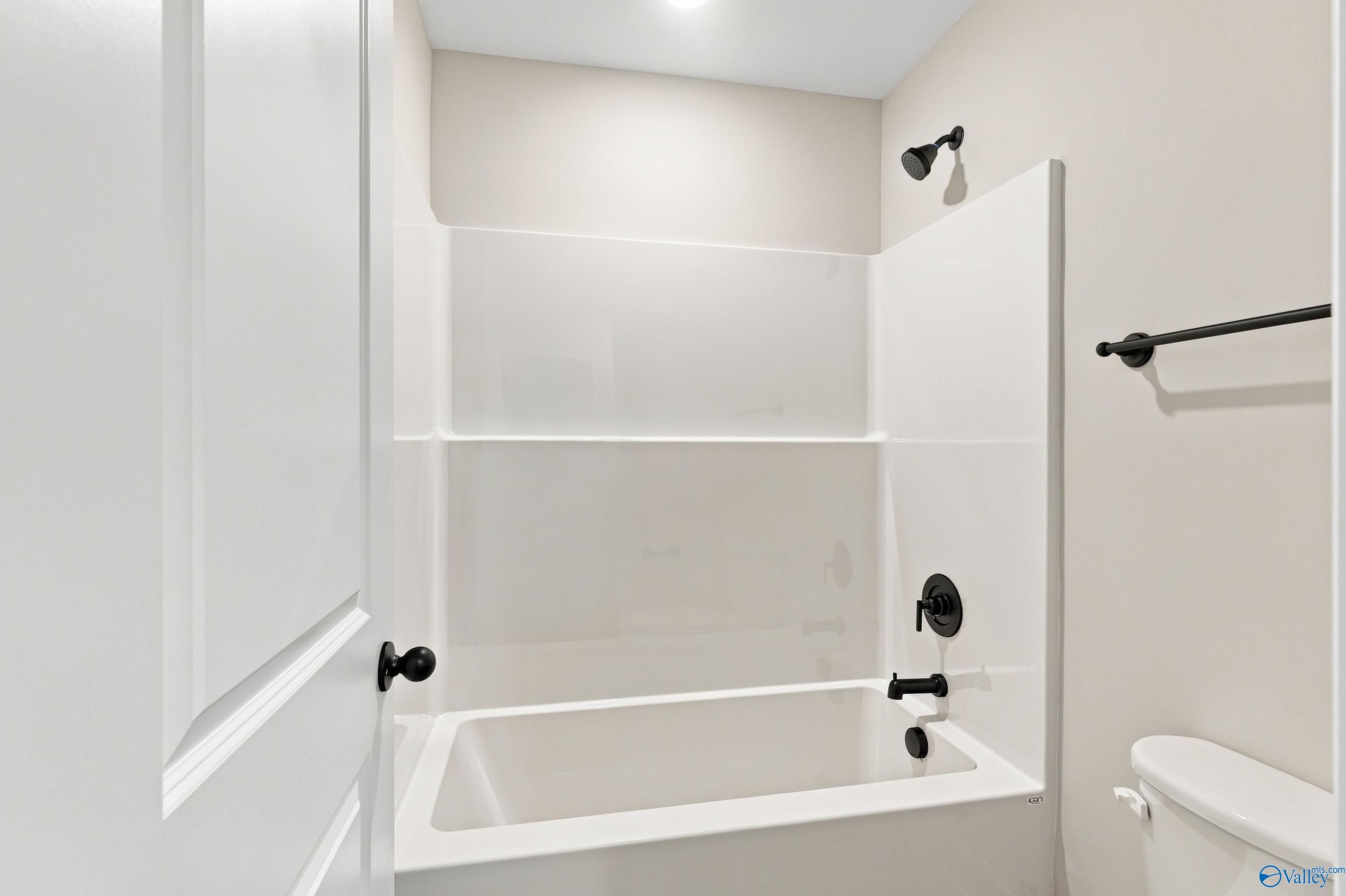 White tub-shower combo with matte black fixtures in Davidson Homes The Chelsea B bathroom in Creek Grove, New Market, Alabama