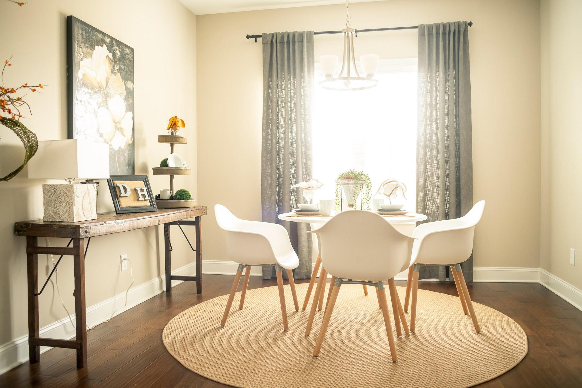 Cozy dining room in Summer Pointe Madison Alabama with white round table, molded chairs, wooden console, artwork and natural light