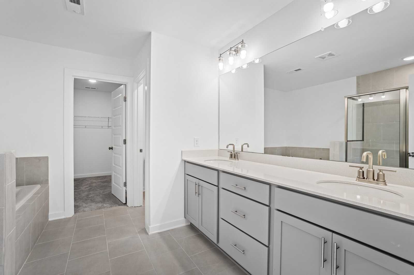 Modern master bathroom with double vanity, glass shower, soaking tub, and walk-in closet in The Logan B, Calista Farms, White House, TN