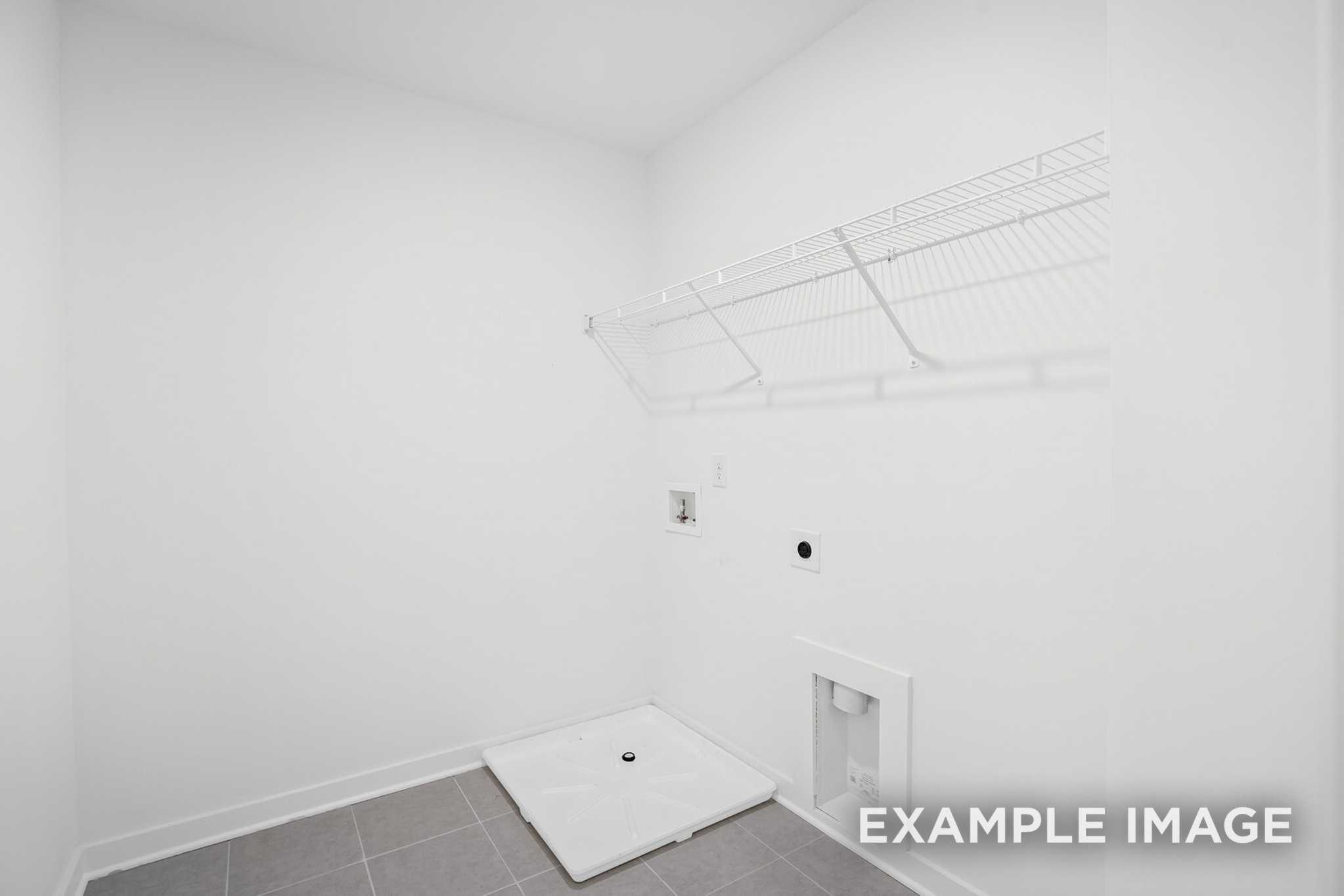 Spacious laundry room in The Grayson C with wire shelving, utility sink, washer dryer hookups on tiled floor