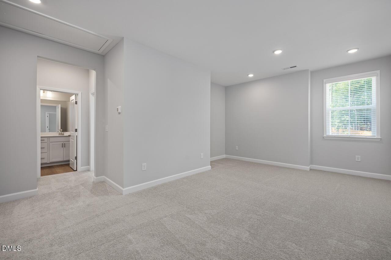 Spacious carpeted bedroom with an en-suite bathroom in The Ashport L floor plan at Sage on North Main, Wake Forest, NC.