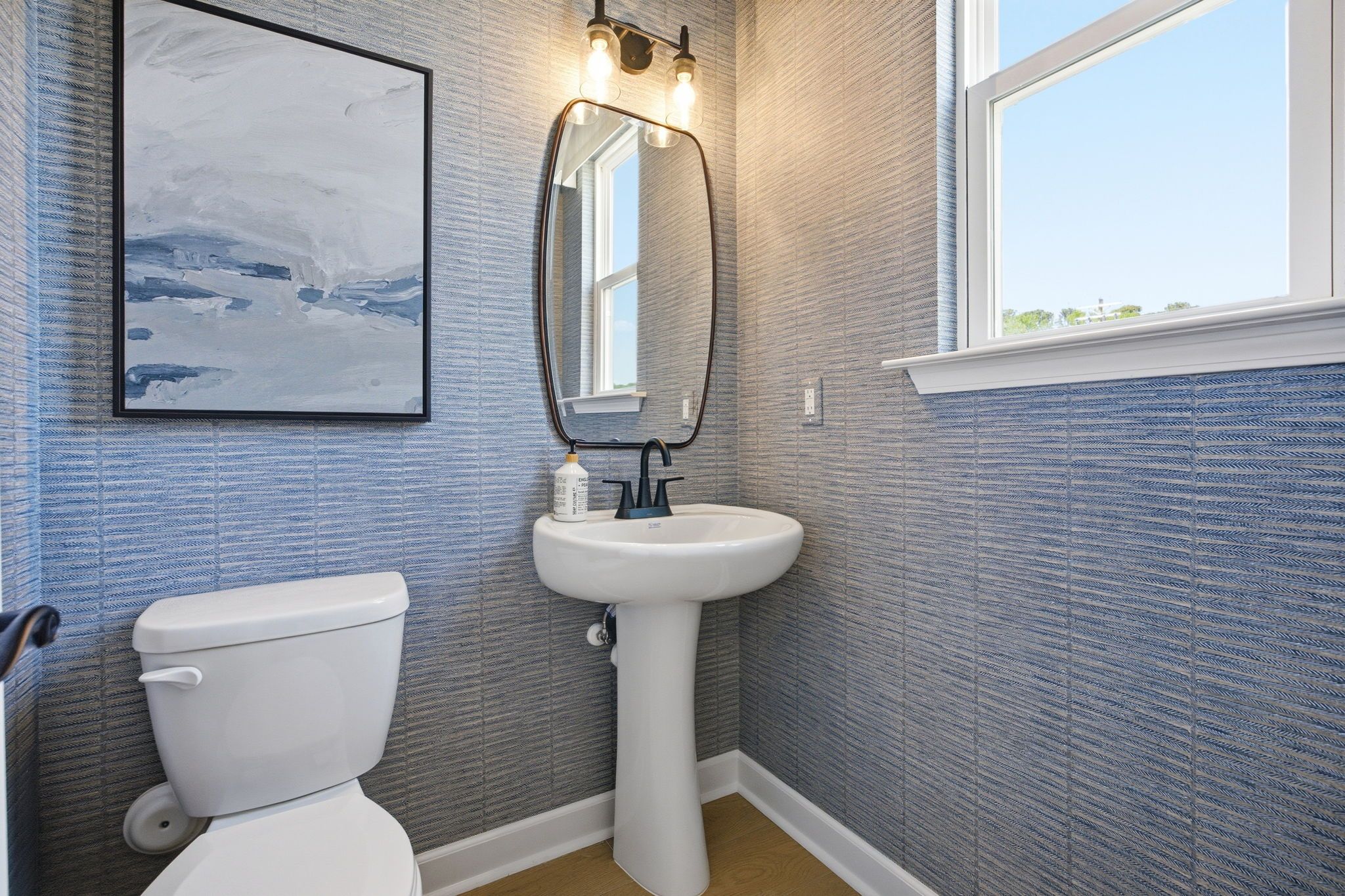 Powder room at Forestville Yard in Knightdale, NC by Davidson Homes featuring textured blue wallpaper and pedestal sink.