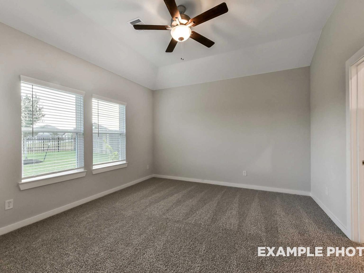 Spacious bedroom with tray ceiling and ceiling fan in The Brookside F floor plan by Davidson Homes in Crosby, Texas.