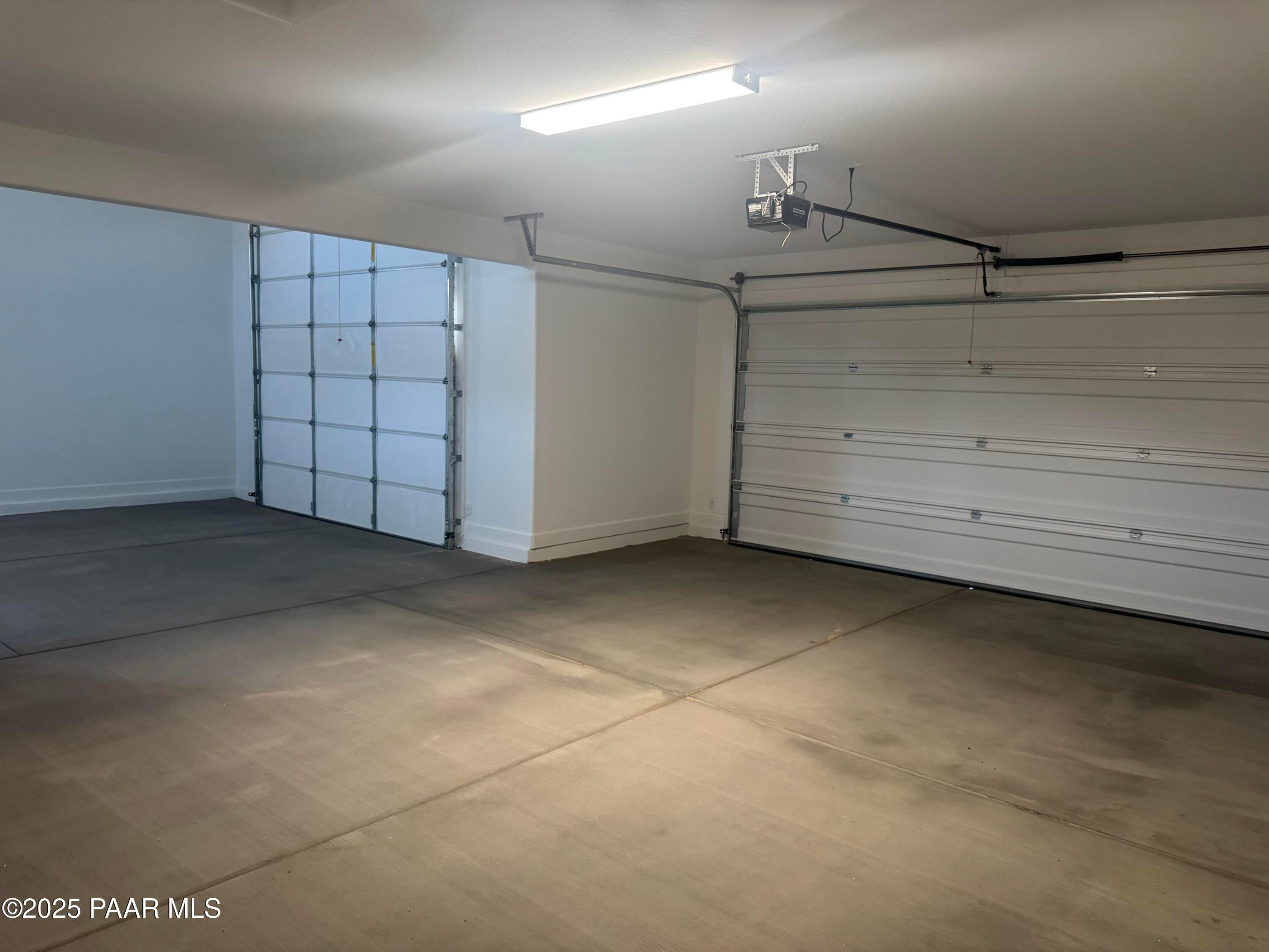 Spacious empty 2-car garage with overhead doors and concrete floor in The Summit B home, Evermore Homes, Prescott Valley, Arizona