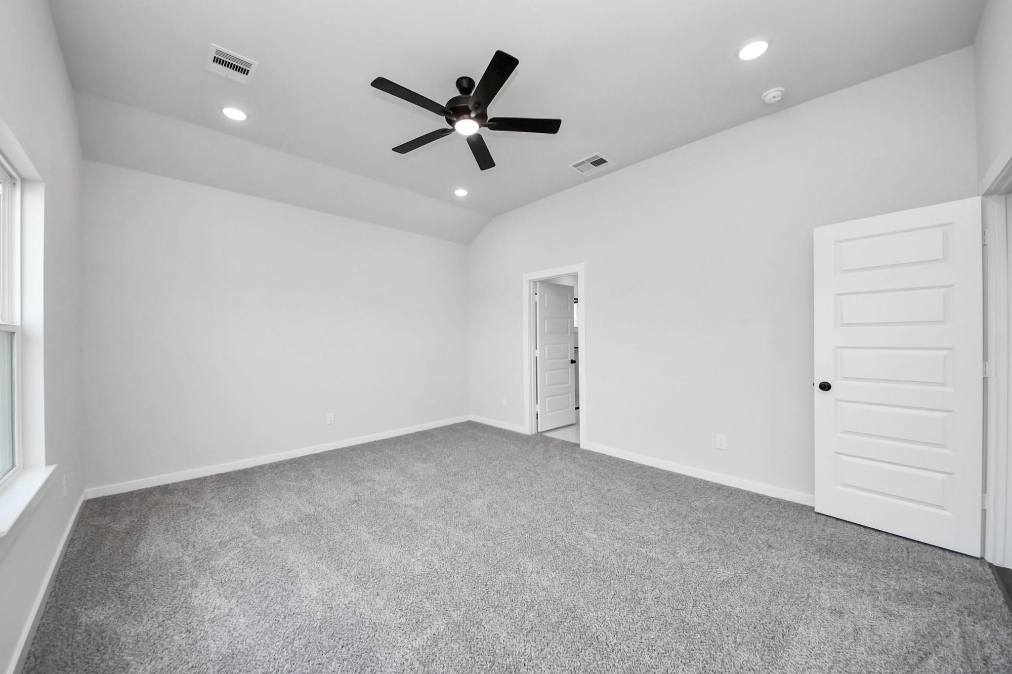 Spacious bedroom with vaulted ceiling and black ceiling fan in The Riviera C floor plan, River Ranch Meadows, Dayton, Texas.