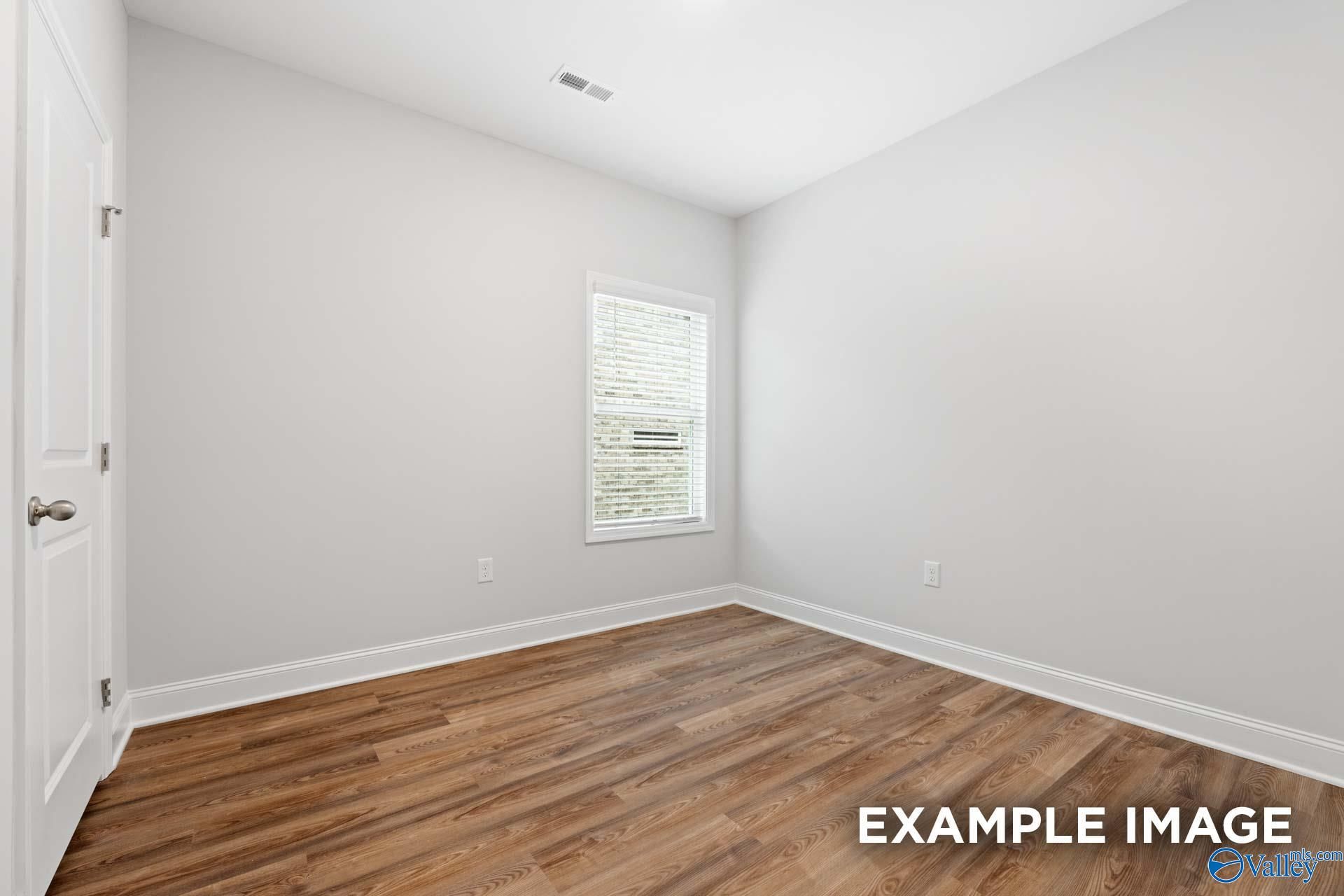 Bright secondary bedroom with light gray walls, hardwood floors, and window blinds in Davidson Homes The Cumberland, Decatur, Alabama