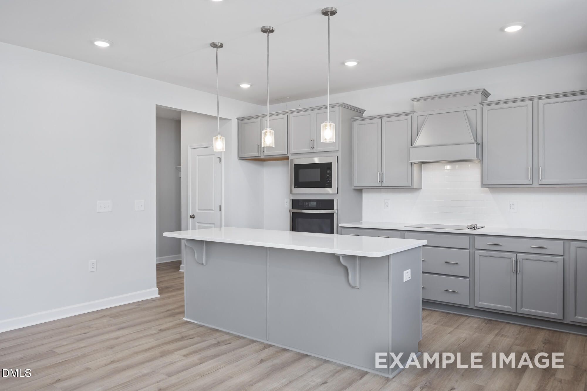 Modern open-concept kitchen with gray cabinets, white island, stainless appliances, and pendant lights in 5-bedroom Davidson Homes The Hickory II B, Lillington, NC