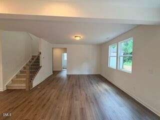 Open-concept living area with wood-style flooring and staircase in The Willow B floor plan at Woodland Crossing, Zebulon, NC.