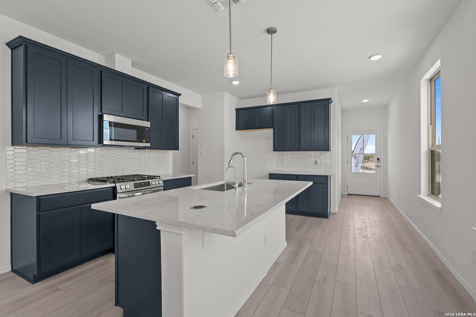 Modern kitchen with navy blue cabinets, white quartz island, and tile backsplash in The Gillian C by Davidson Homes.