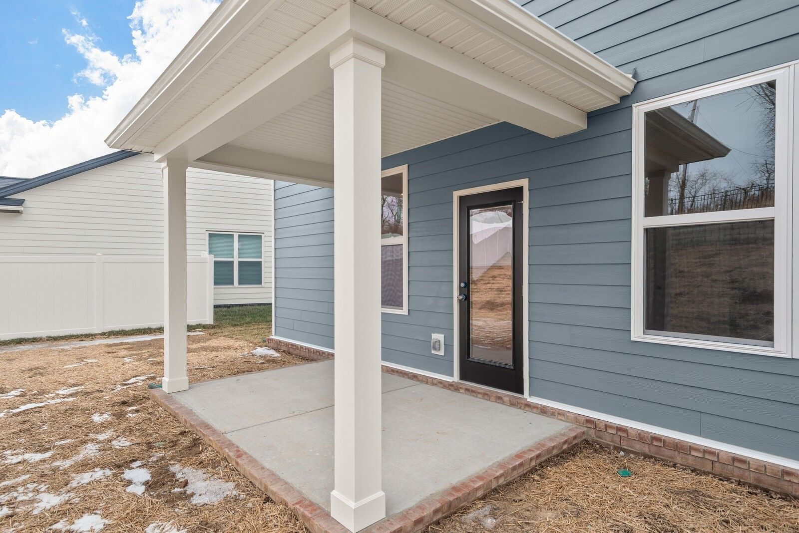 Light blue two-story home with covered porch, white columns, glass door, and windows in Woods Crossing, Gallatin, Tennessee