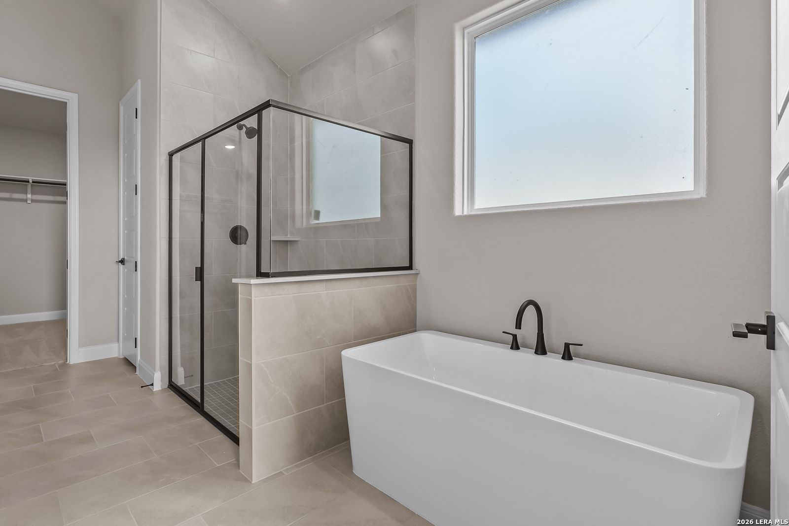 Freestanding soaking tub and glass walk-in shower in master bathroom of Davidson Homes The Foster E in Castroville, Texas