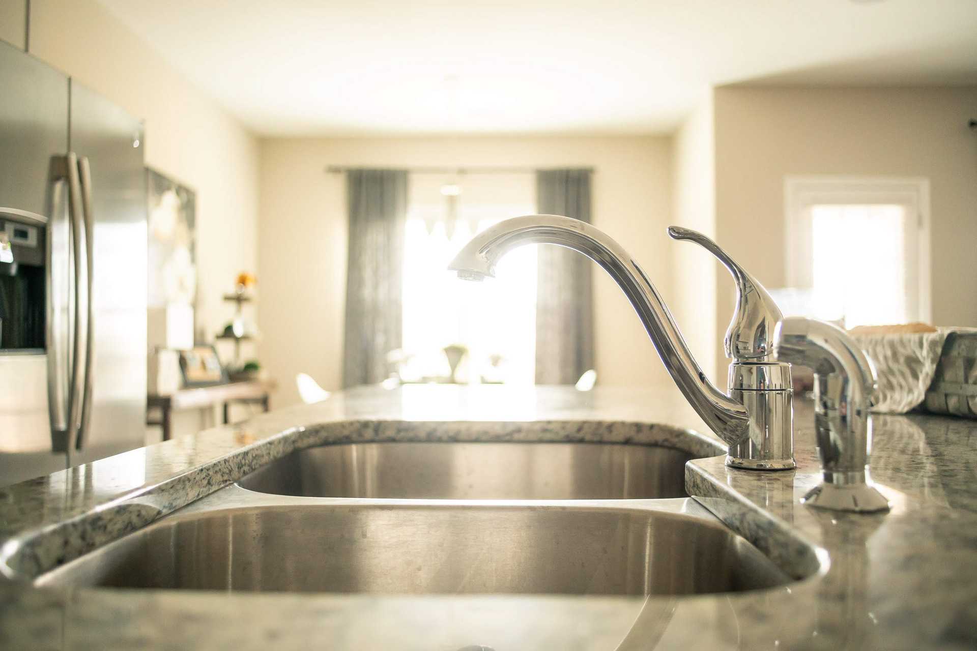 Spacious modern kitchen at Summer Pointe in Madison, Alabama with granite counters, double stainless sink, and open dining area