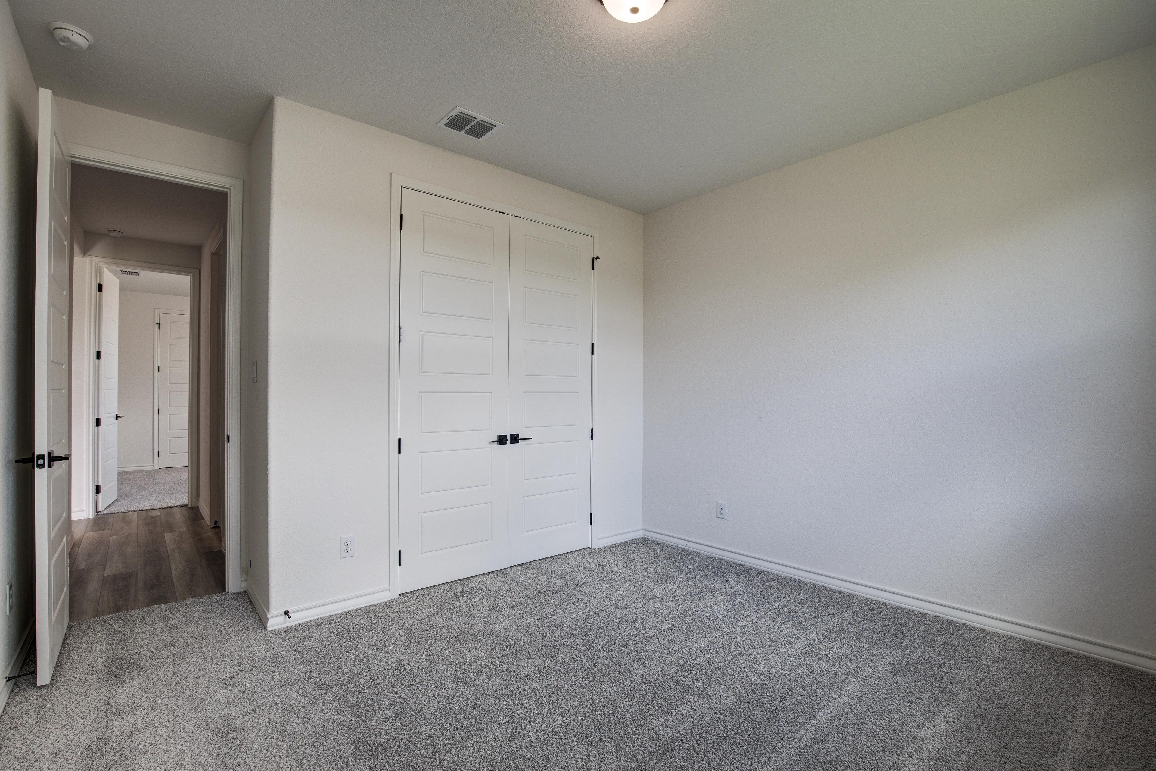 Spacious secondary bedroom in The Lanier F with gray carpet, white walls, paneled closet doors, and hallway access
