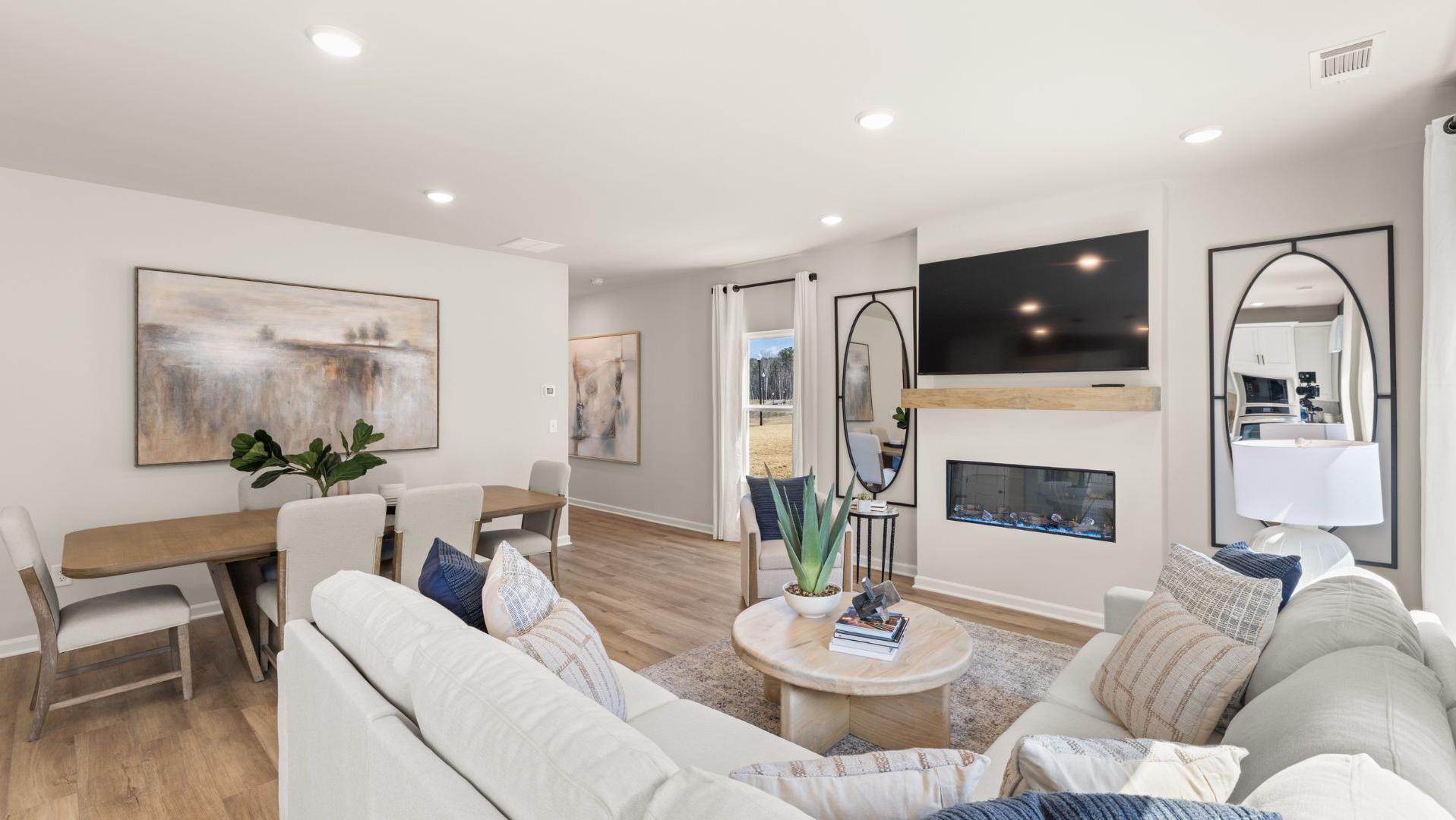 Spacious Links Crossing model home interior by Davidson Homes: white sectional sofa, gas fireplace, dining table, abstract art, plants