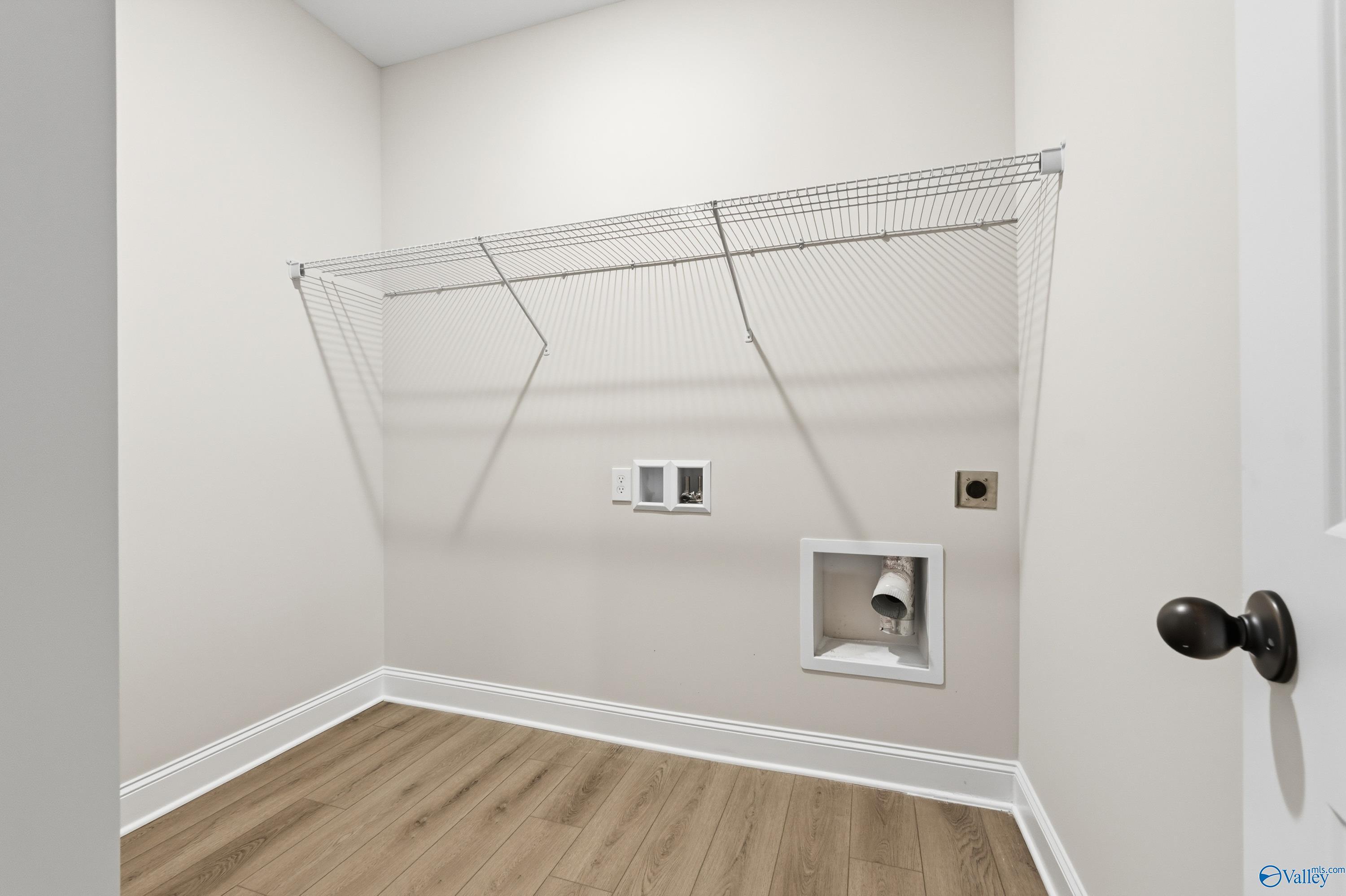 Bright laundry room with wire shelving, washer/dryer hookups and hardwood floors in Davidson Homes The Daphne D, Arab, Alabama