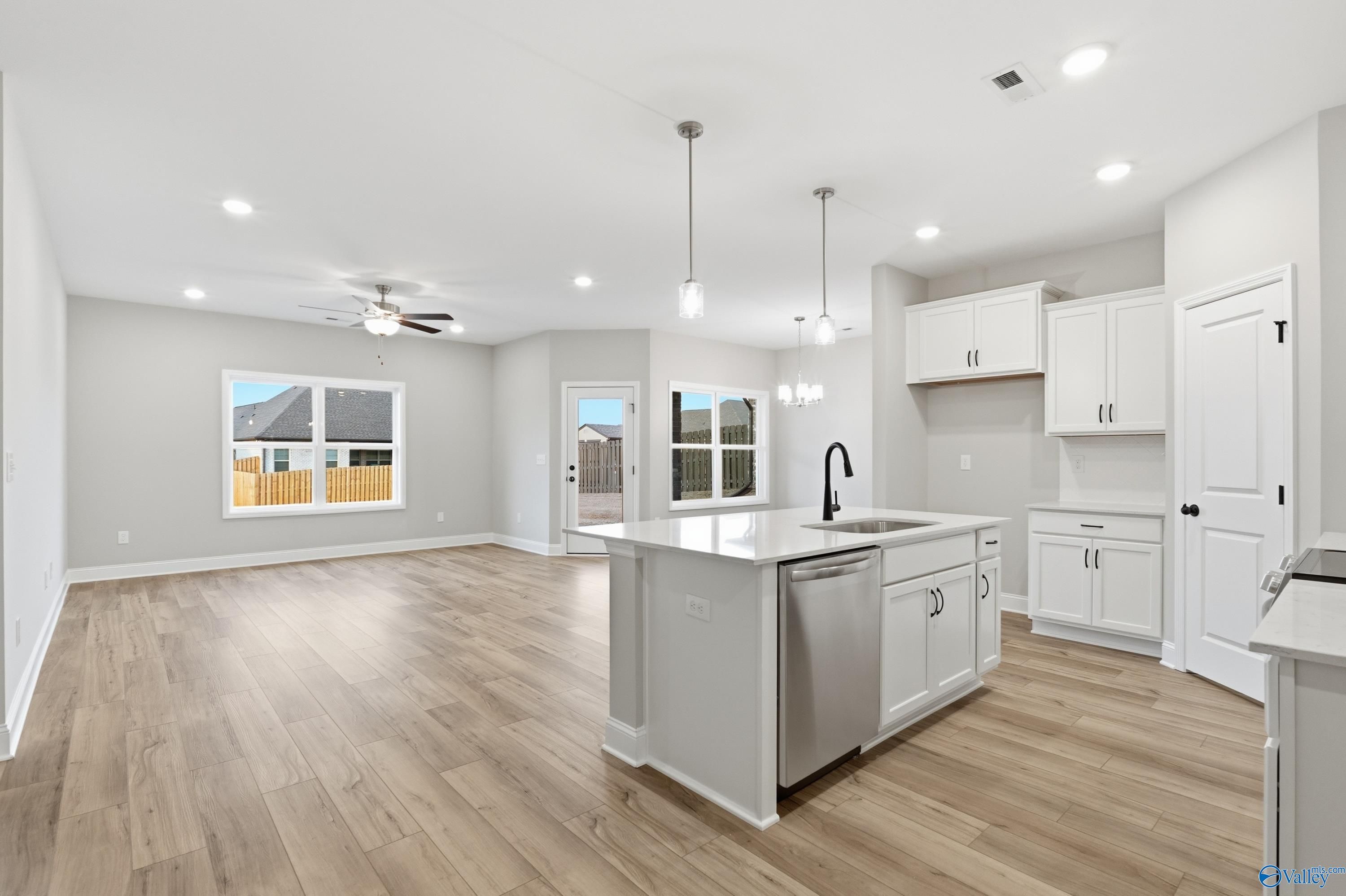 Bright open kitchen with white island sink, cabinets, and backyard views in Davidson Homes The Daphne C, Harvest, Alabama