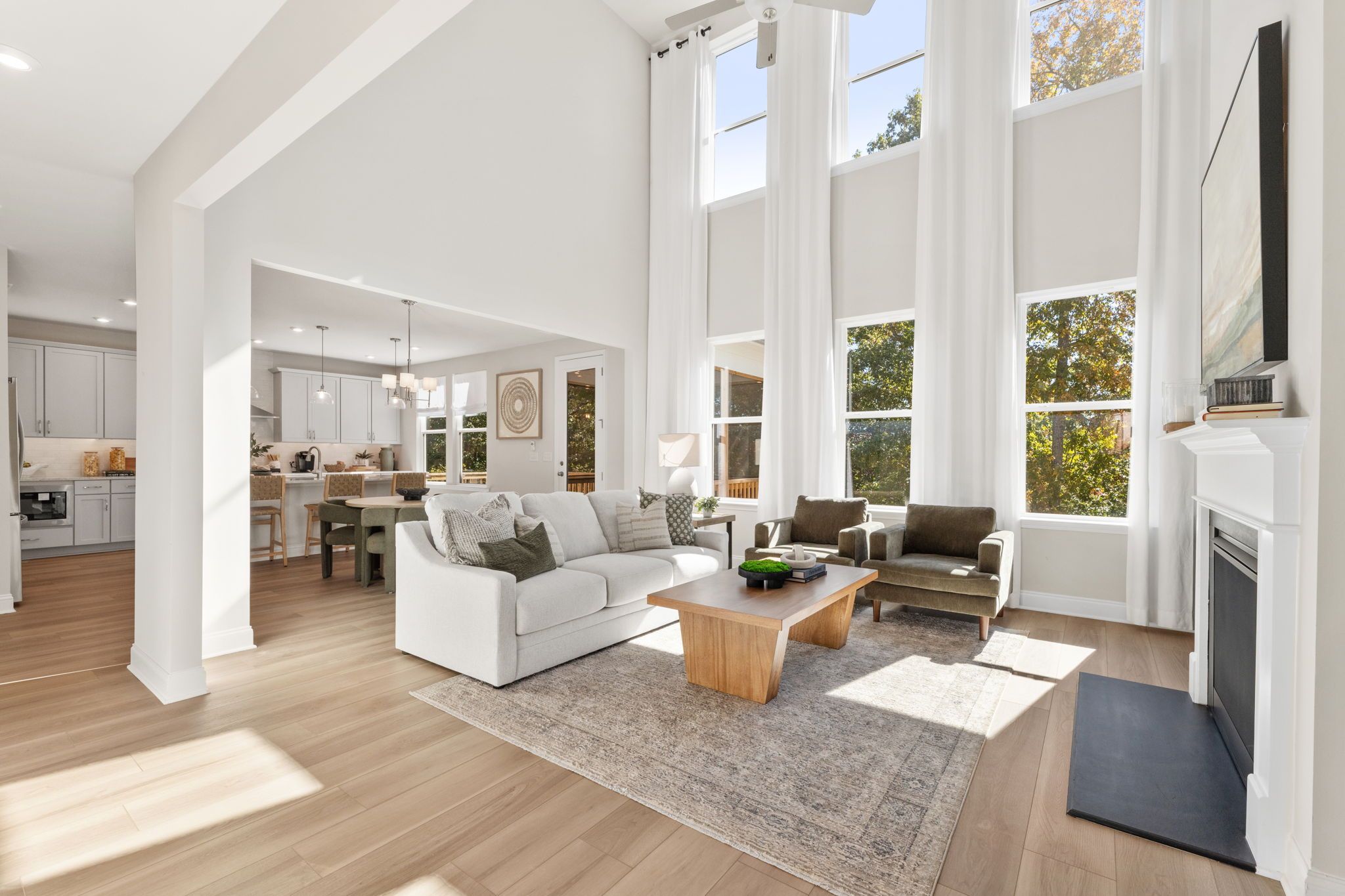 Open-concept kitchen dining living area in Fern Hollow Buford GA with white quartz island hardwood floors pendant lights
