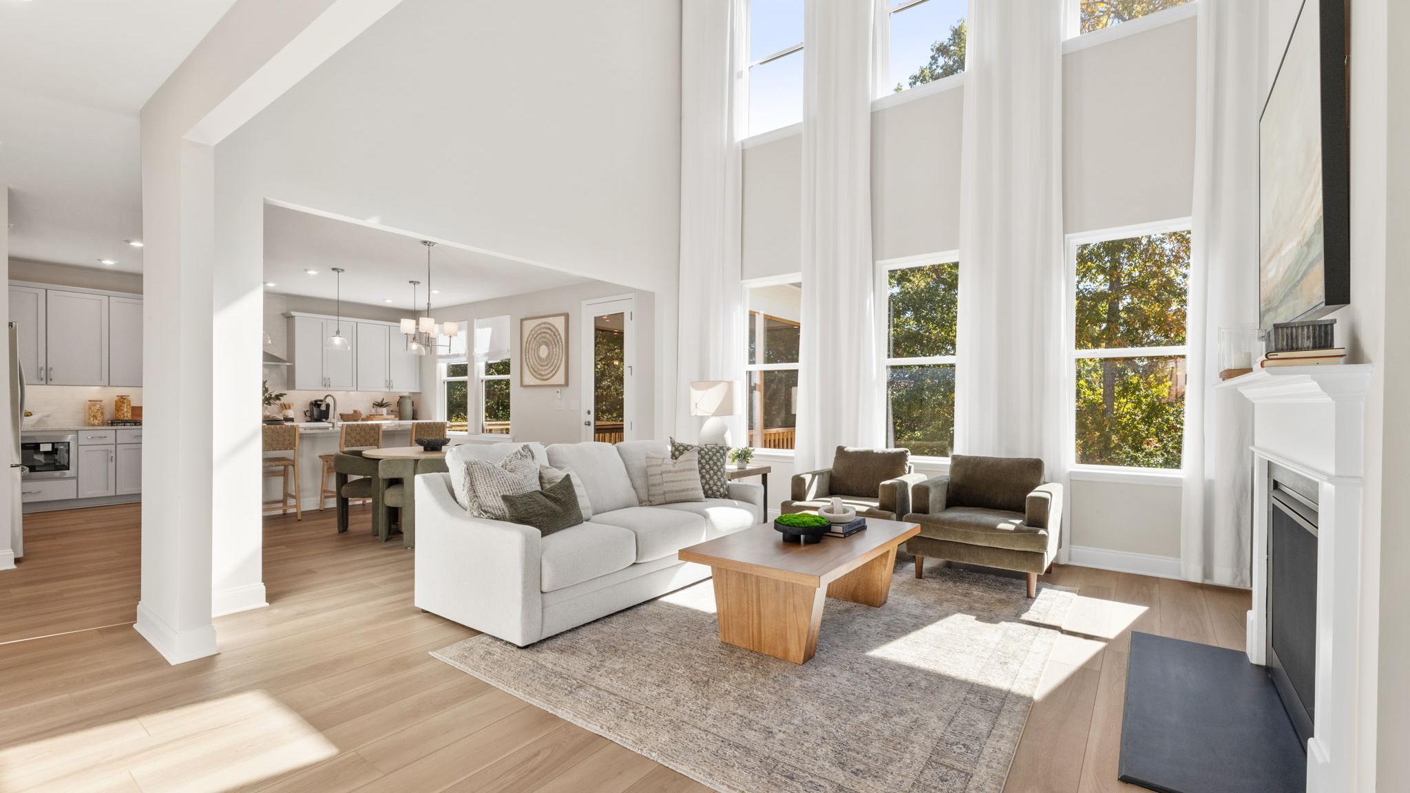 Open-concept kitchen dining living area in Fern Hollow Buford GA with white quartz island hardwood floors pendant lights