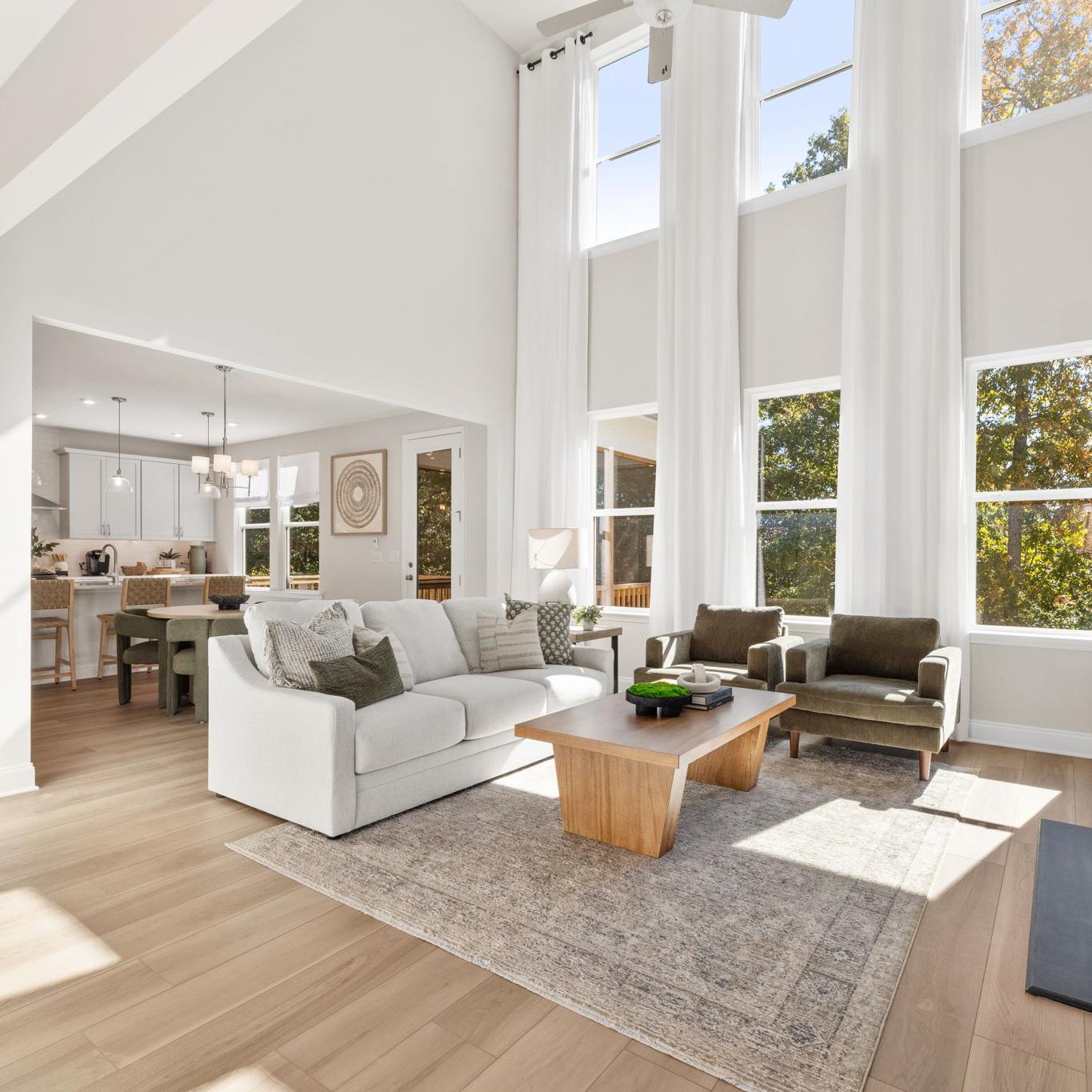 Open-concept kitchen dining living area in Fern Hollow Buford GA with white quartz island hardwood floors pendant lights