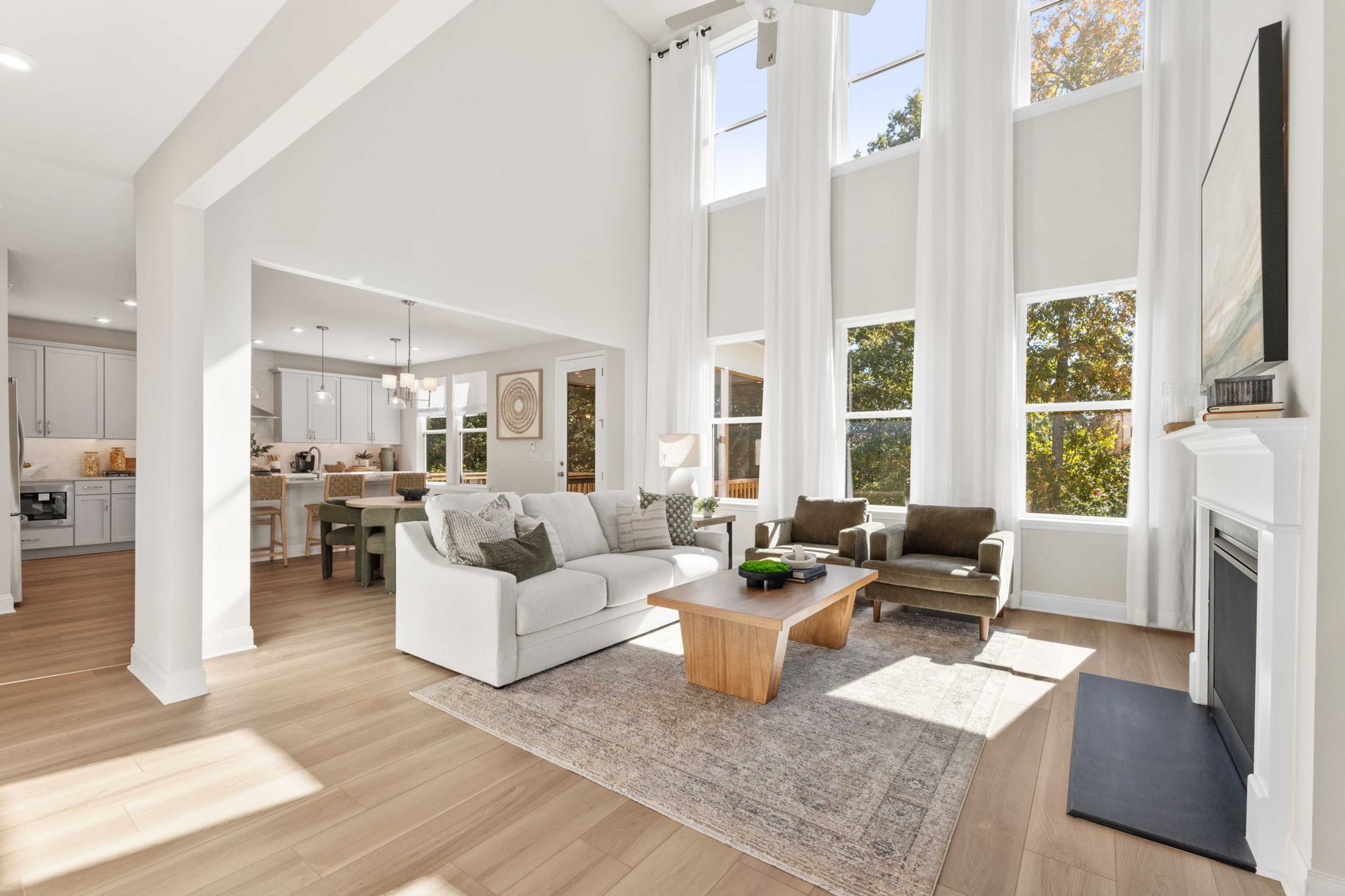 Spacious open-concept living room at Melody Lakeside Estates in Buford GA with vaulted ceilings, hardwood floors, white sofa, and fireplace