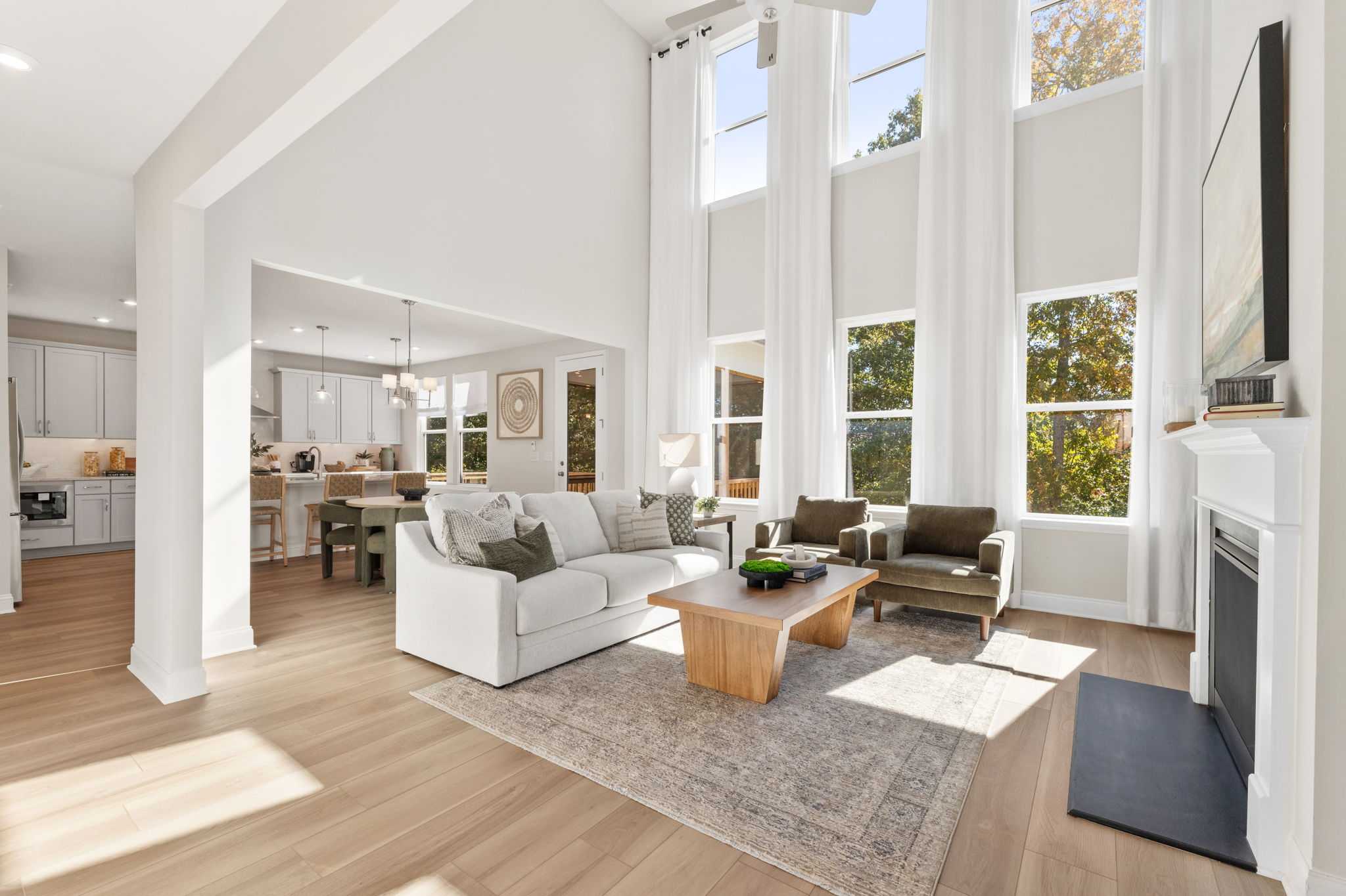 Spacious open-concept living room at Melody Lakeside Estates in Buford GA with vaulted ceilings, hardwood floors, white sofa, and fireplace