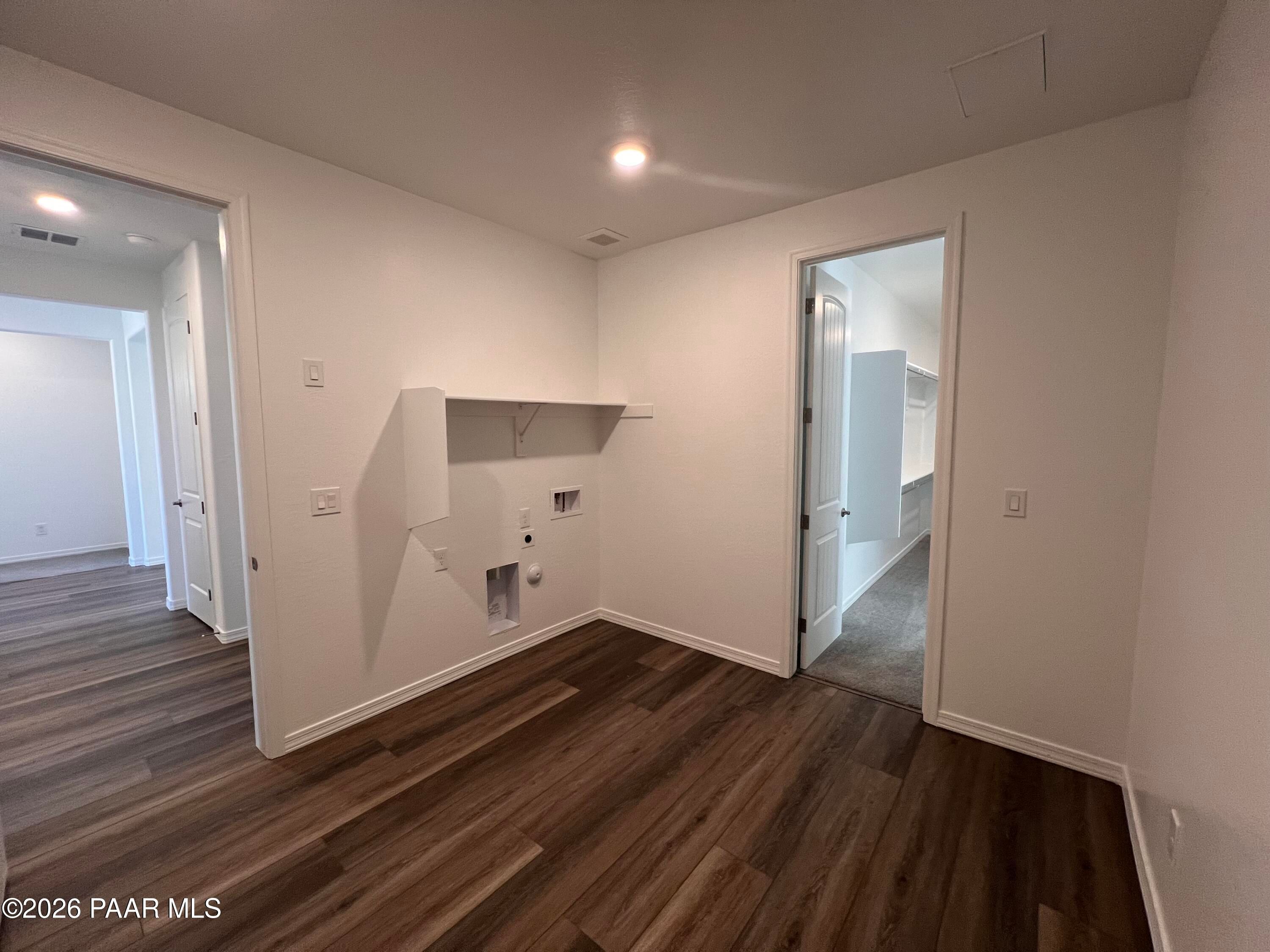 Bright laundry room with white built-in cabinets, washer/dryer hookups, and luxury vinyl plank flooring in Davidson Homes Sunrise II A, Prescott, AZ