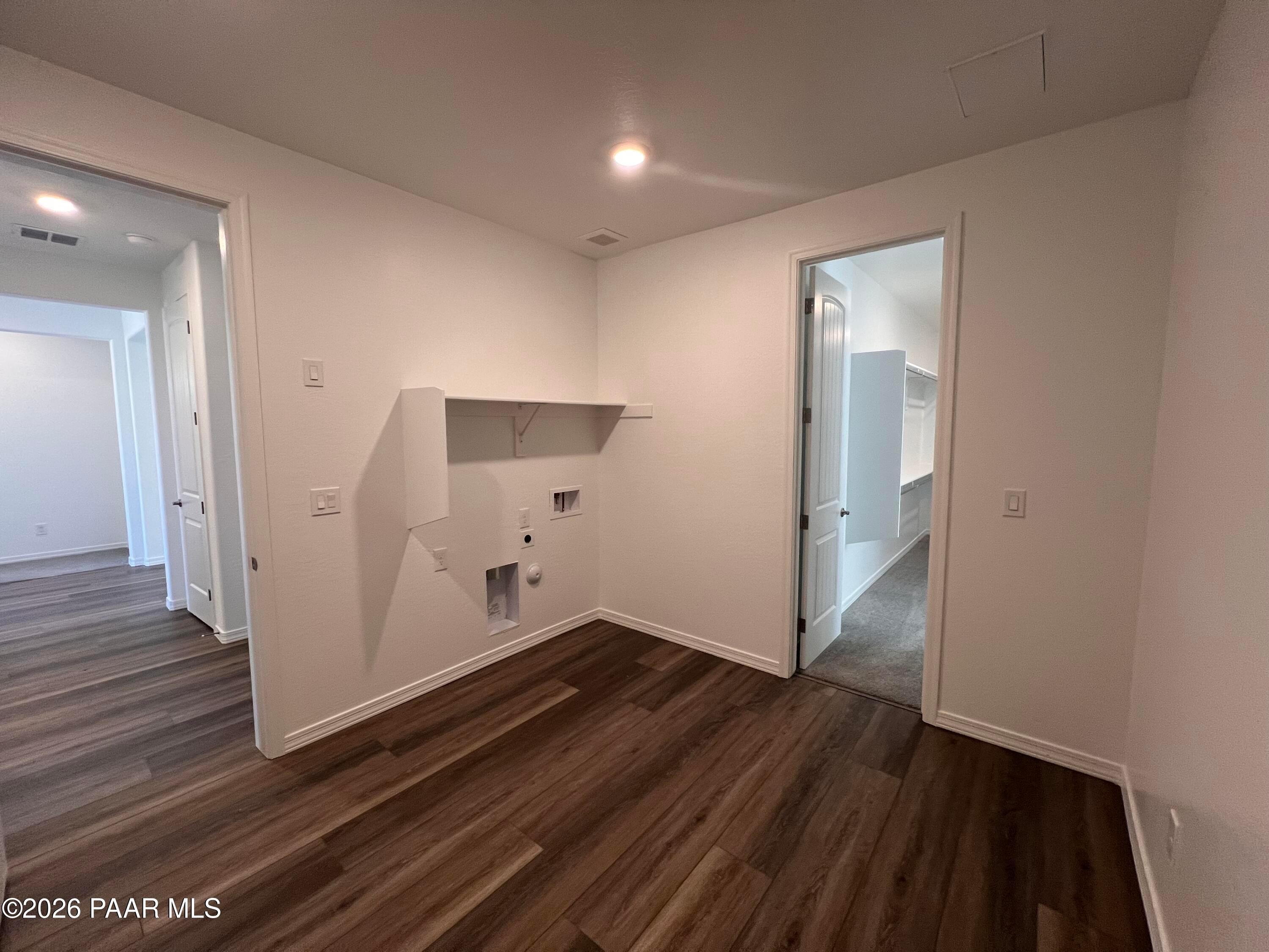 Bright laundry room with white built-in cabinets, washer/dryer hookups, and luxury vinyl plank flooring in Davidson Homes Sunrise II A, Prescott, AZ