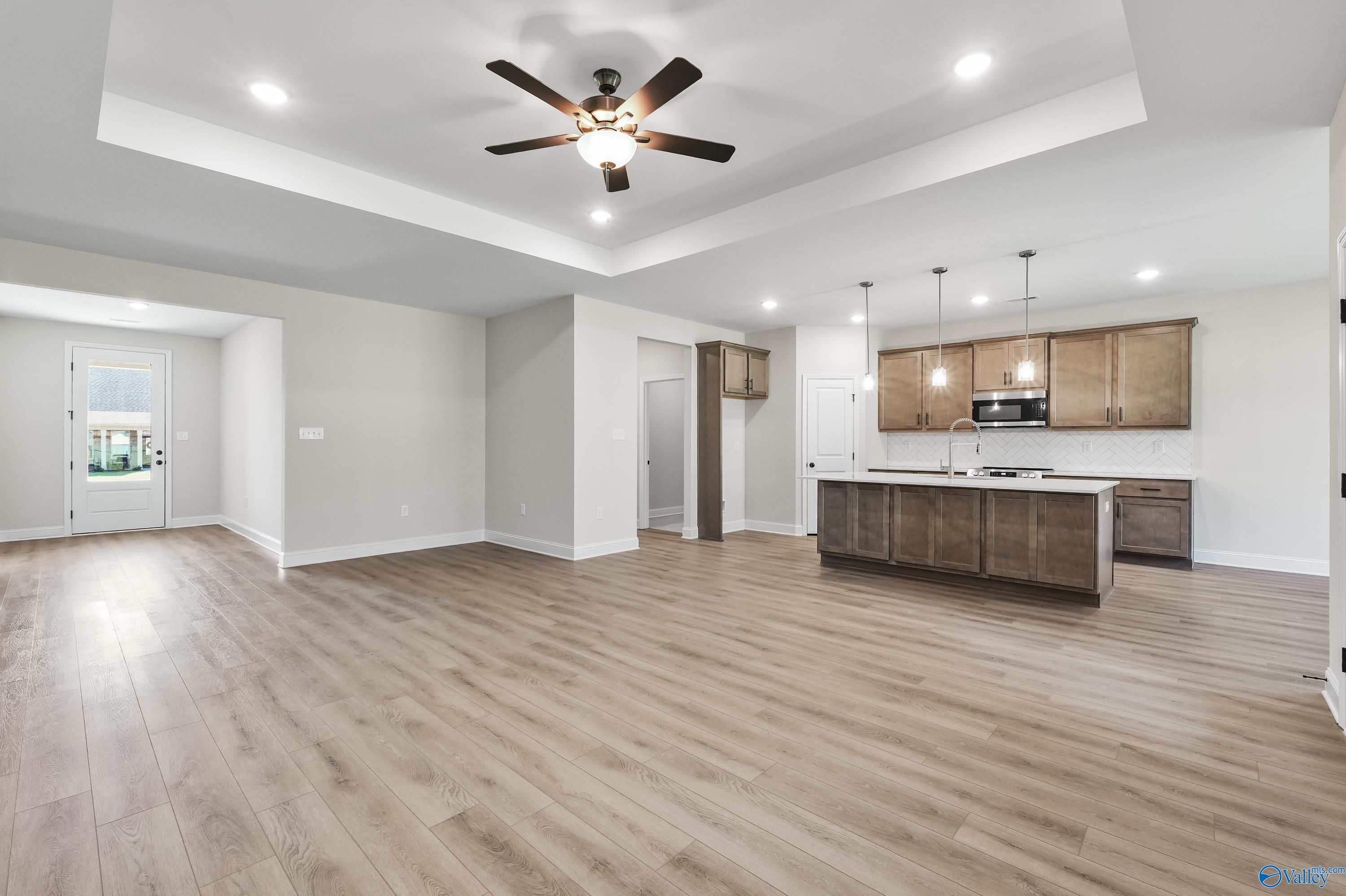 Open-concept kitchen with shaker cabinets, island sink, and adjacent living space in The Montgomery C by Davidson Homes, Decatur AL