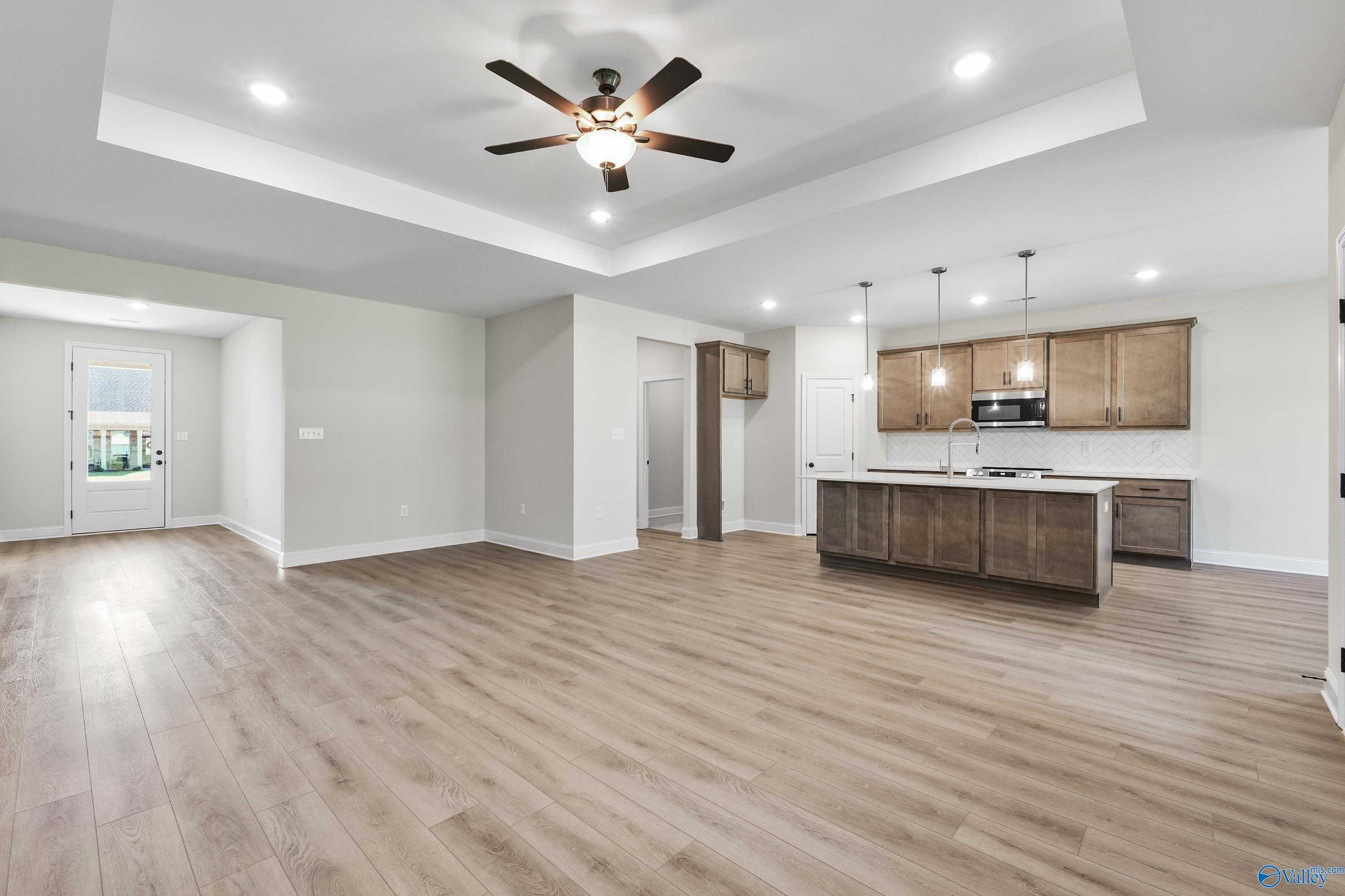 Open-concept kitchen with shaker cabinets, island sink, and adjacent living space in The Montgomery C by Davidson Homes, Decatur AL