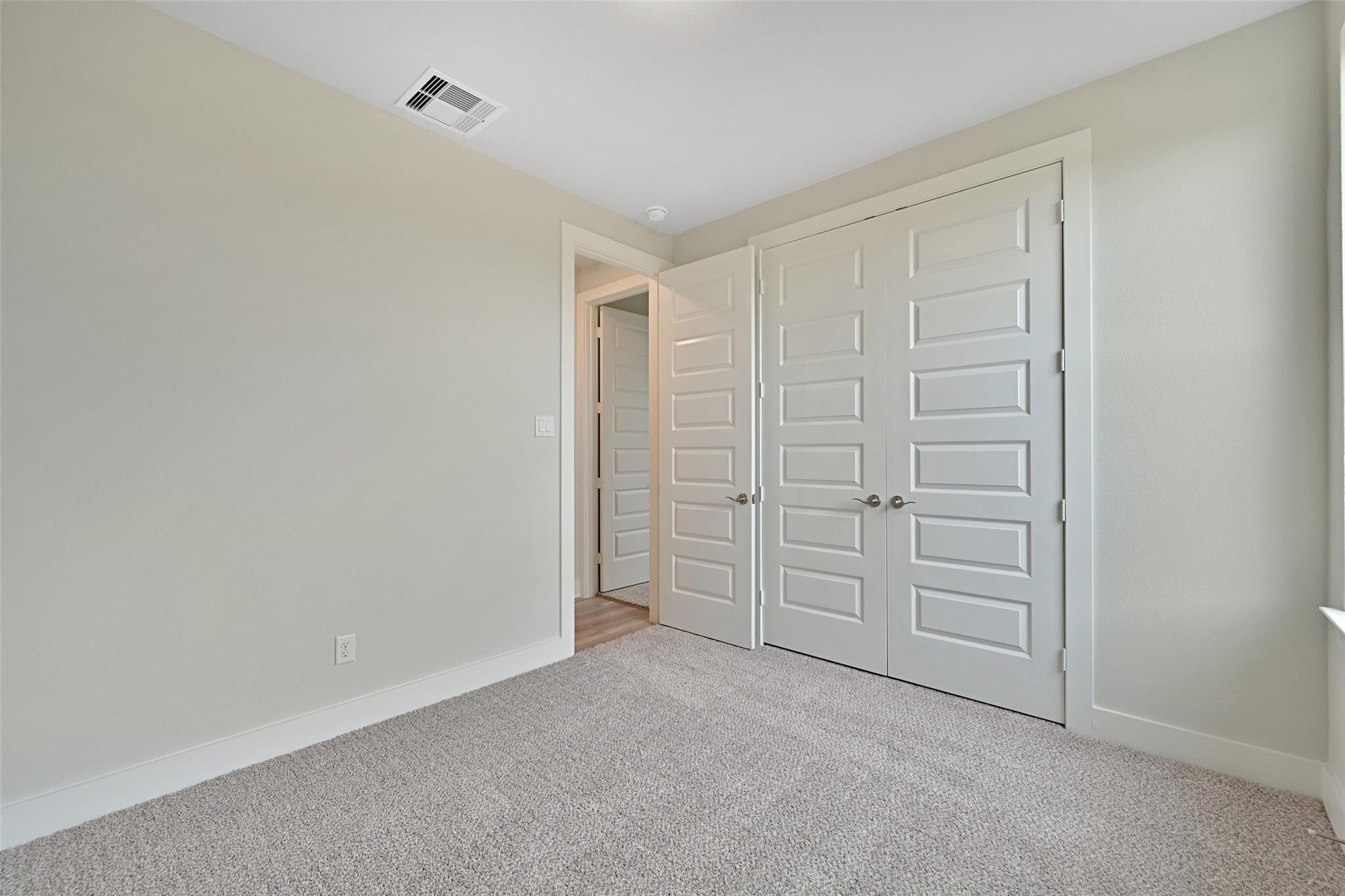 Spacious master bedroom with walk-in closet double doors, beige walls, and carpet in Davidson Homes The Edward A, Lago Mar, Texas City