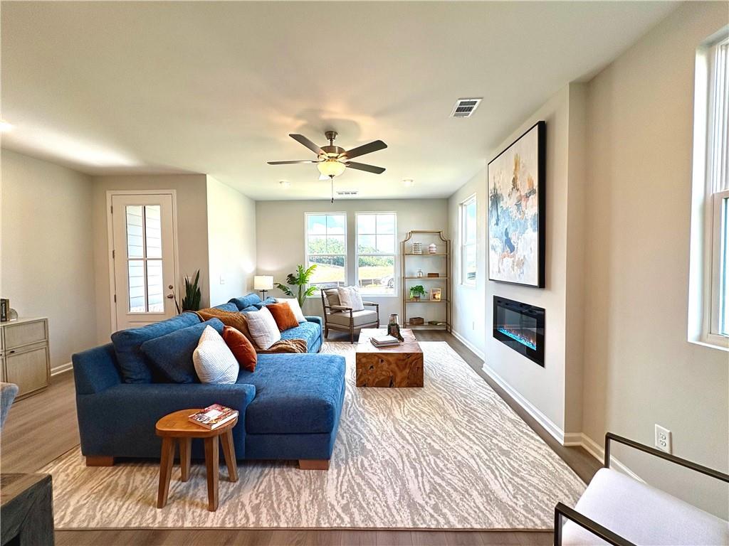 Inviting living room with blue sectional sofa, gas fireplace, abstract art, and natural light in Davidson Homes The Monroe A, Emerson, Georgia