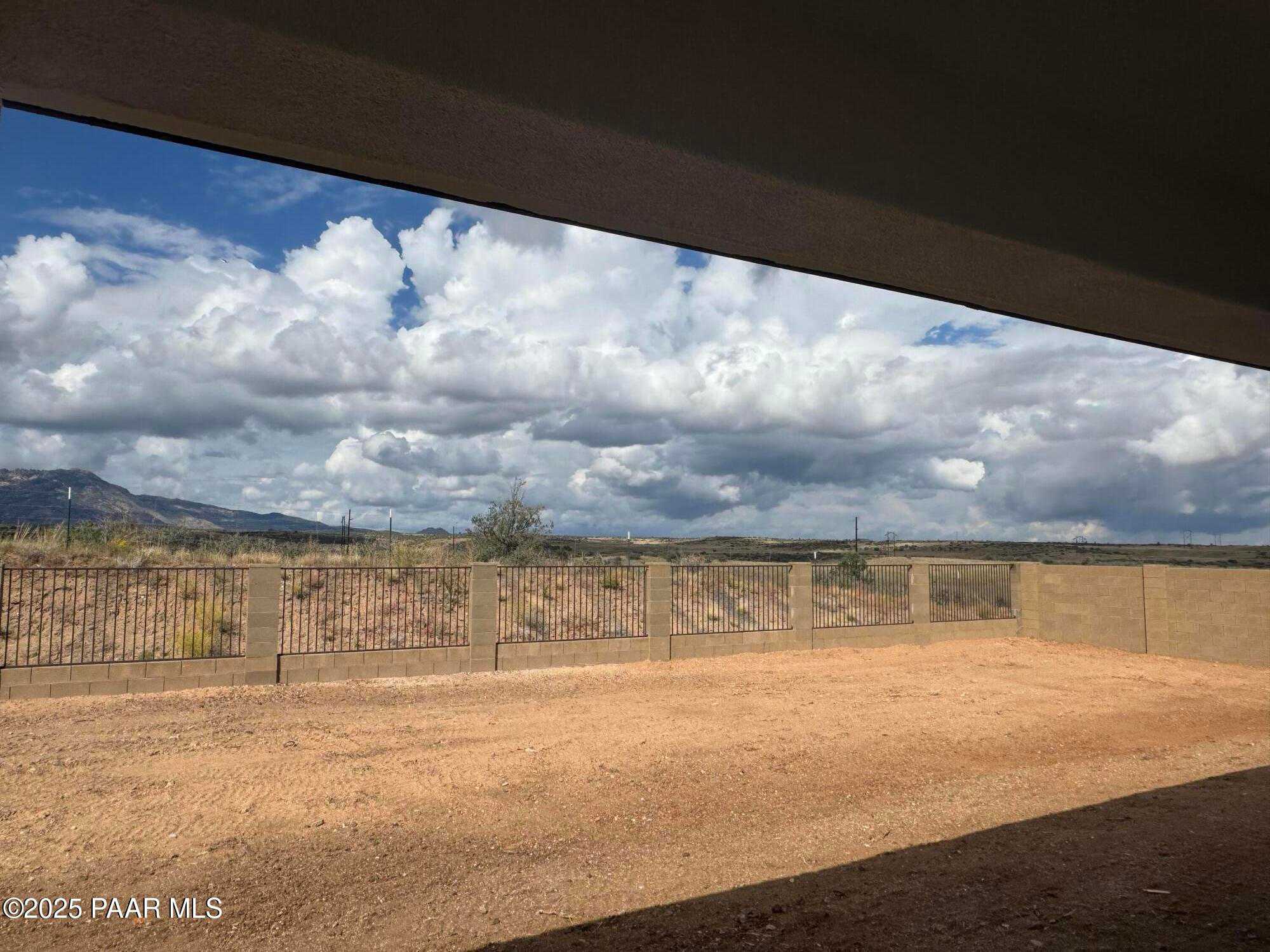 Expansive desert backyard with mountain views through wrought iron fence in Davidson Homes The Monarch E, Prescott Arizona