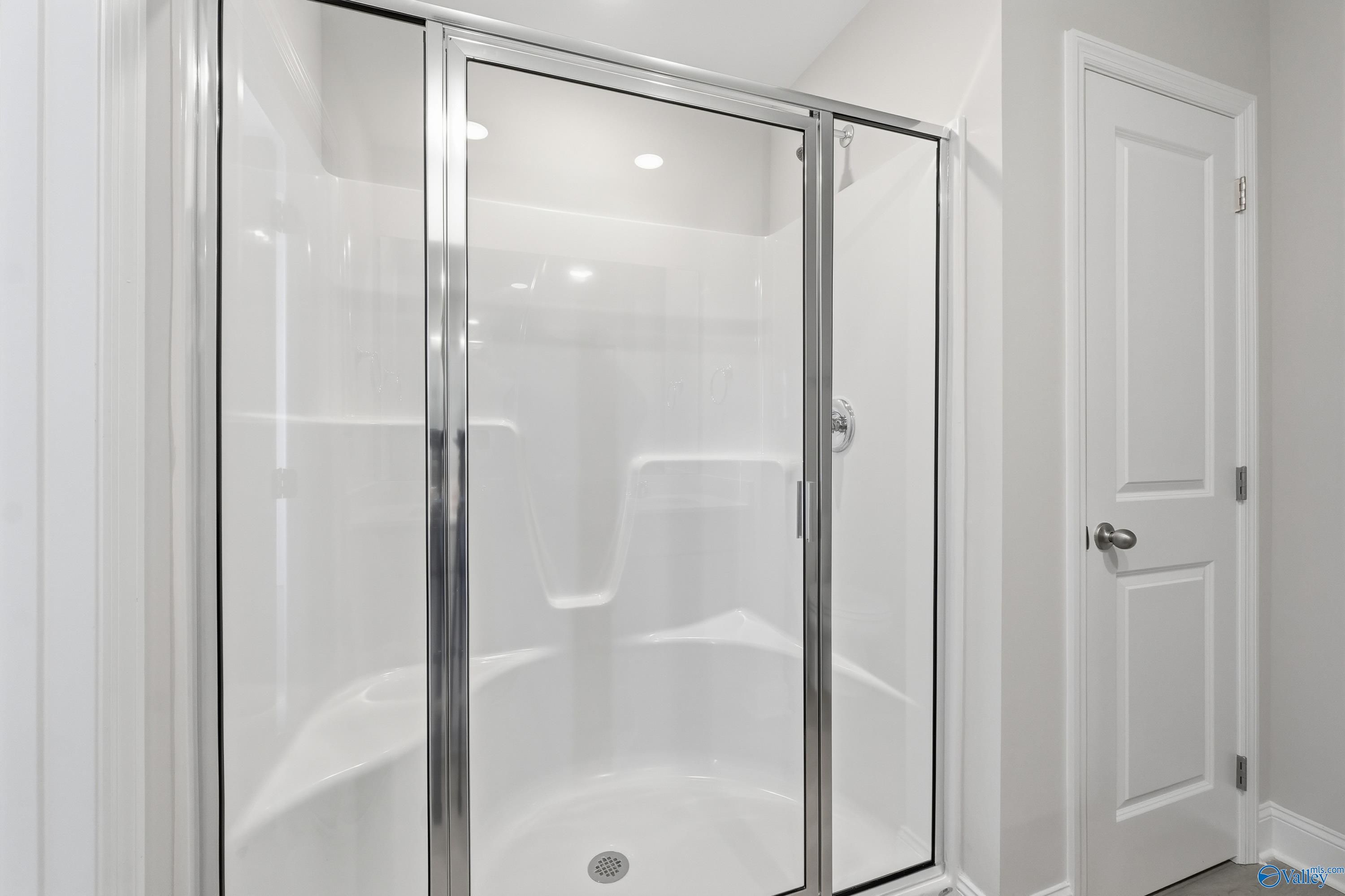 Modern frameless glass walk-in shower with white subway tile in The Butler master bath, Davidson Homes, New Market, Alabama