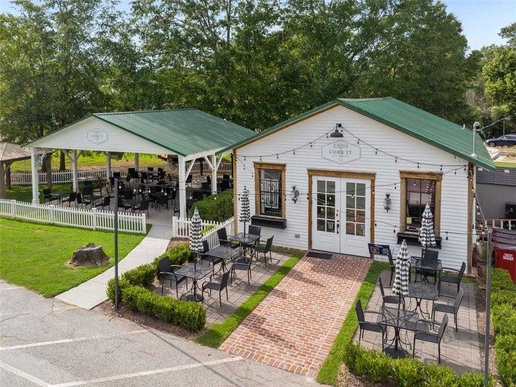 Cozy white coffee shop with green roof, outdoor patio seating, and lush greenery in Wehunt Meadows, Hoschton, Georgia