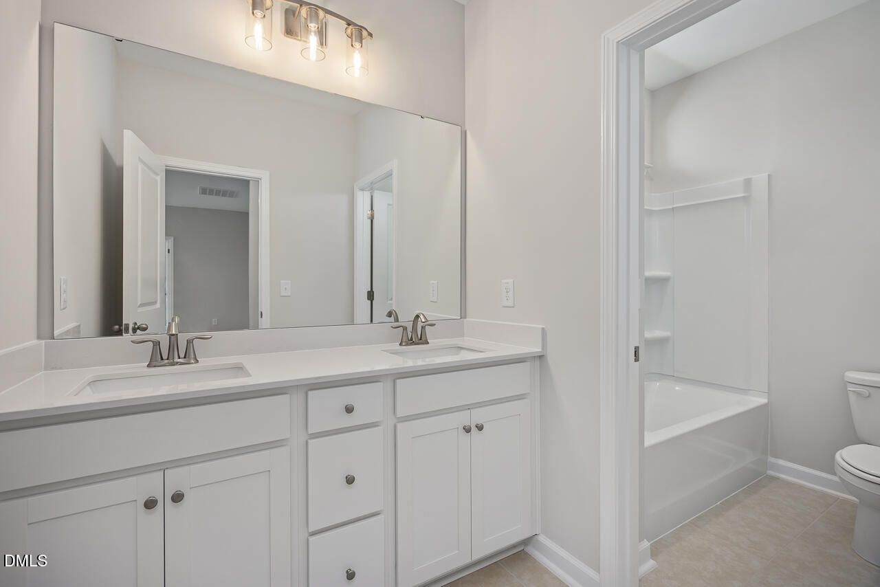 Modern bathroom with dual-sink vanity and tub-shower combo in The Ashport L plan at Sage on North Main, Wake Forest, NC.