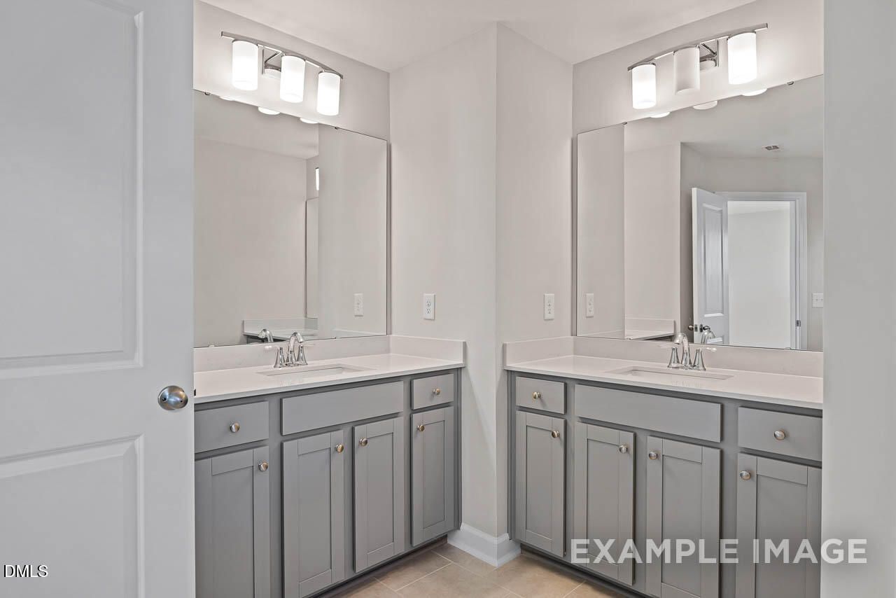 Dual vanity bathroom with gray cabinets and white countertops in Davidson Homes The Graham floor plan, Fuquay-Varina, NC.