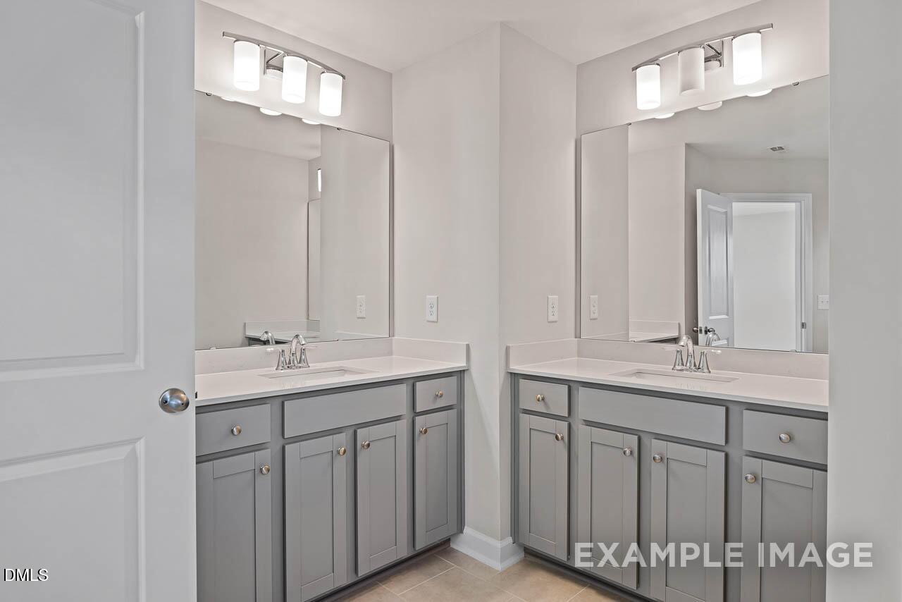 Dual vanity bathroom with gray cabinets and white countertops in Davidson Homes The Graham floor plan, Fuquay-Varina, NC.