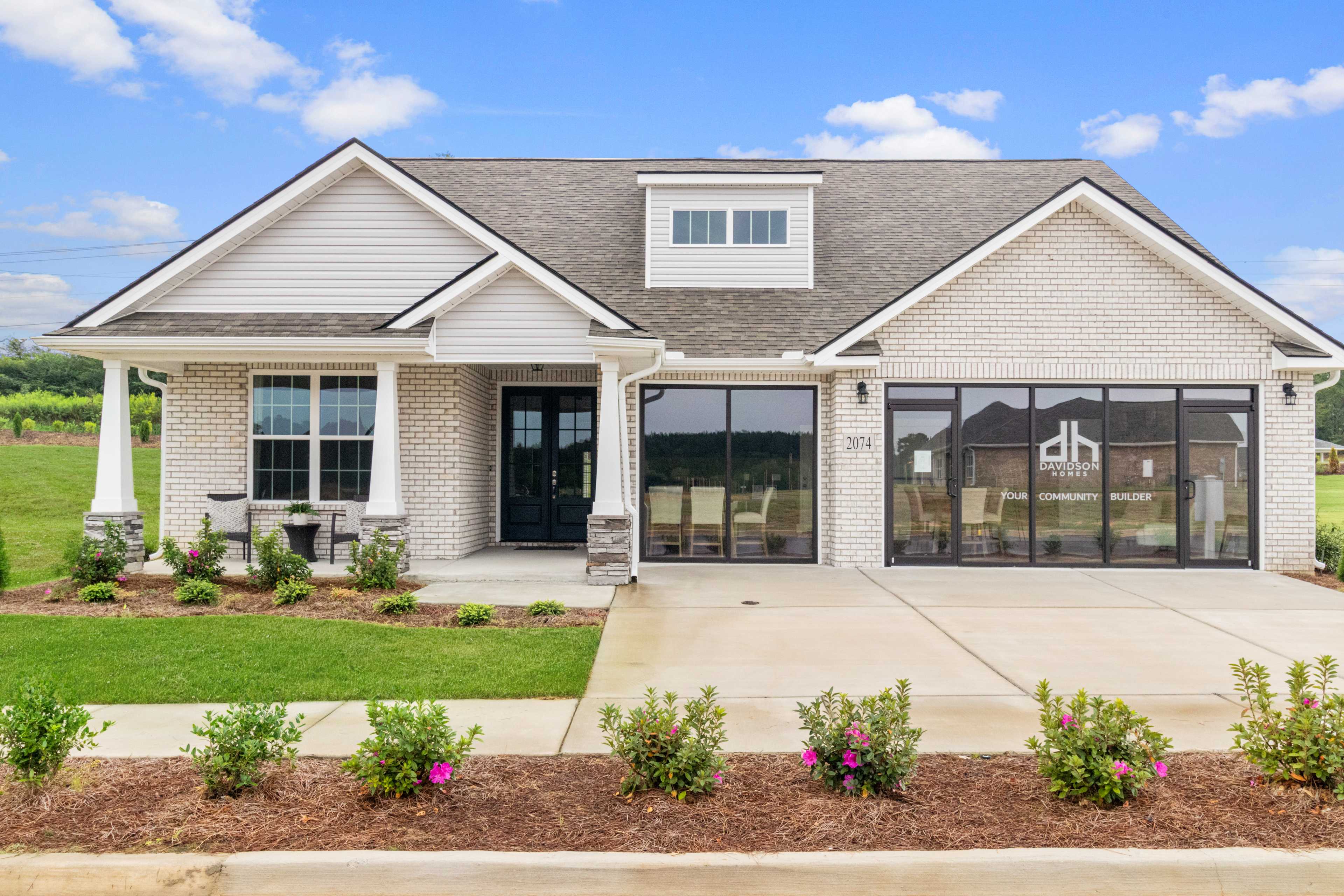 Craftsman-style home exterior at North Ridge in Cullman Alabama with covered porch, brick base, large windows, and landscaped yard