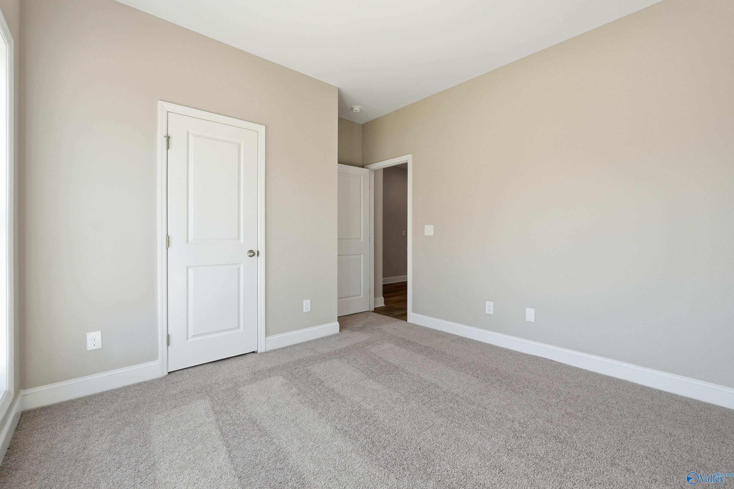 Spacious bedroom with beige walls, white doors, and carpet flooring in Davidson Homes The Franklin C, New Market, Alabama