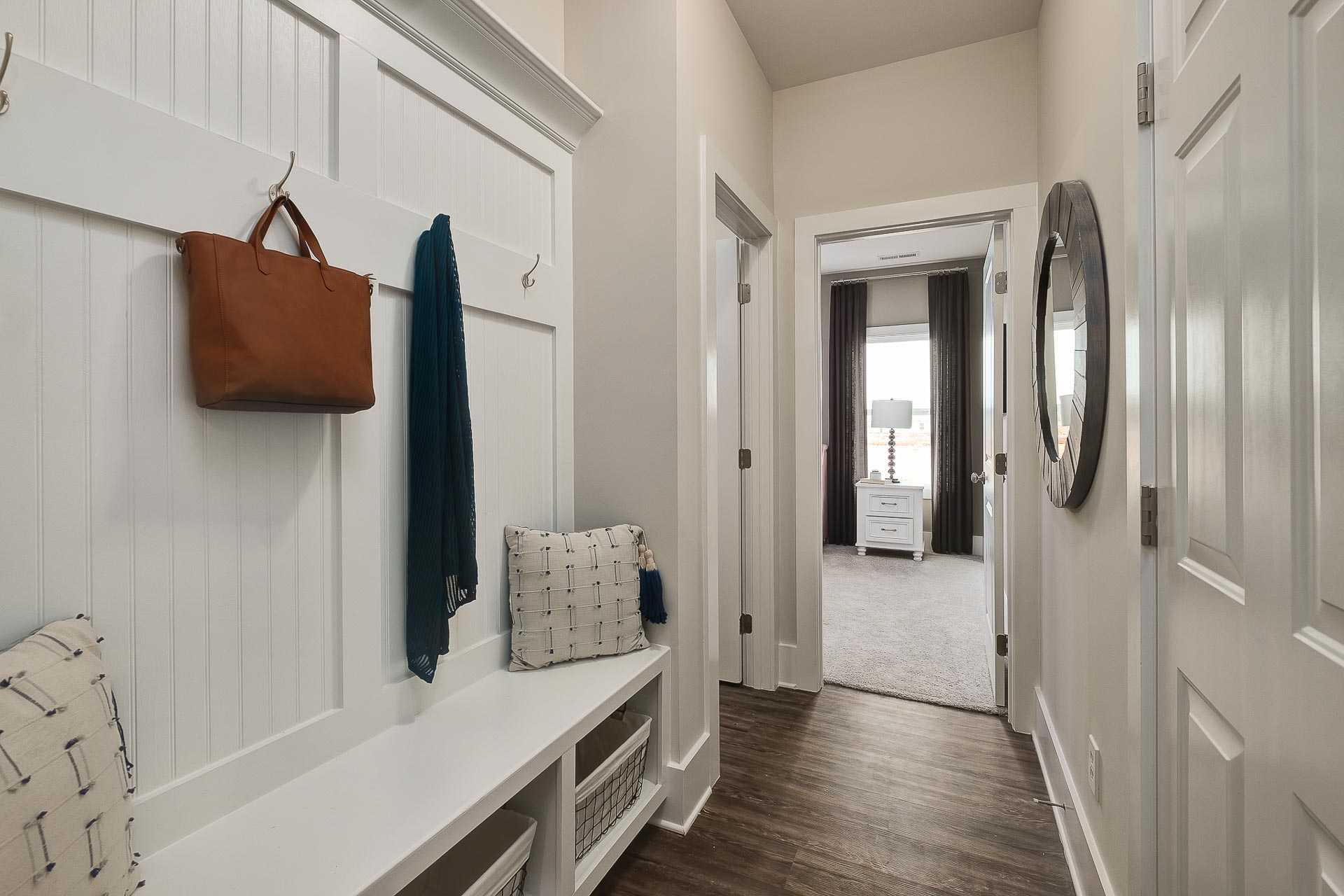Spacious mudroom in The Everett C home with white beadboard lockers, built-in bench, hanging purse and coat hooks