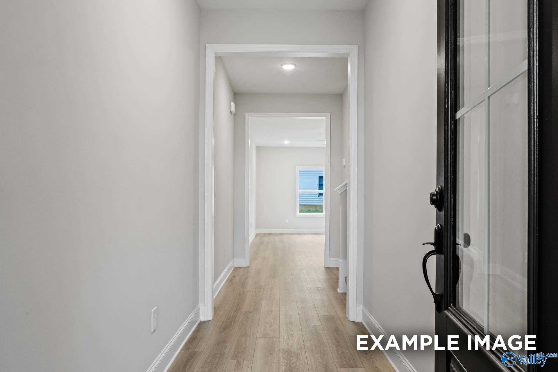 Bright hallway with light gray walls, hardwood floors, and glass door in Davidson Homes The Camden D, Pavilion, Huntsville, Alabama
