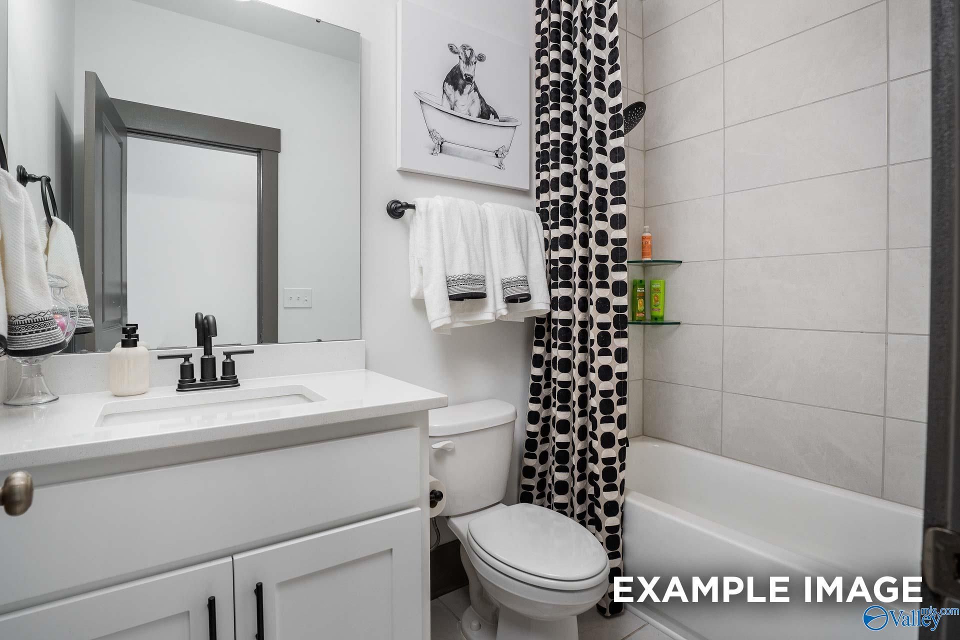 Contemporary guest bathroom with white vanity, soaking tub, polka dot curtain and cow art in Davidson Homes The Rockford B, Madison AL