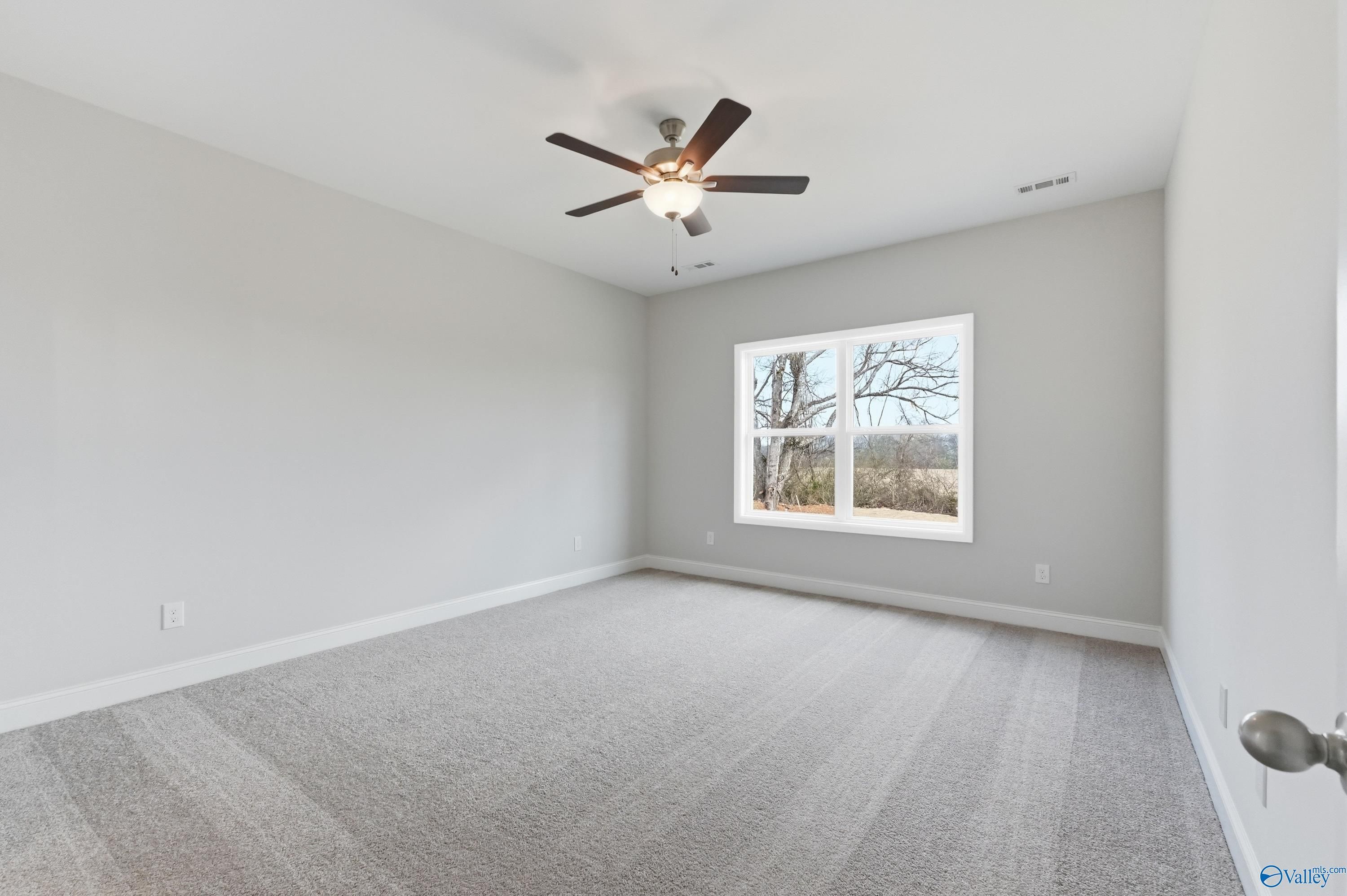 Spacious secondary bedroom with gray walls, carpet floor, ceiling fan, and large window in Davidson Homes The Daphne C, Toney, Alabama