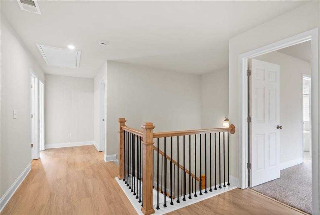 Upstairs hallway with oak hardwood floors, wooden staircase, and white walls in Davidson Homes The Hickory B at Wehunt Meadows, Hoschton