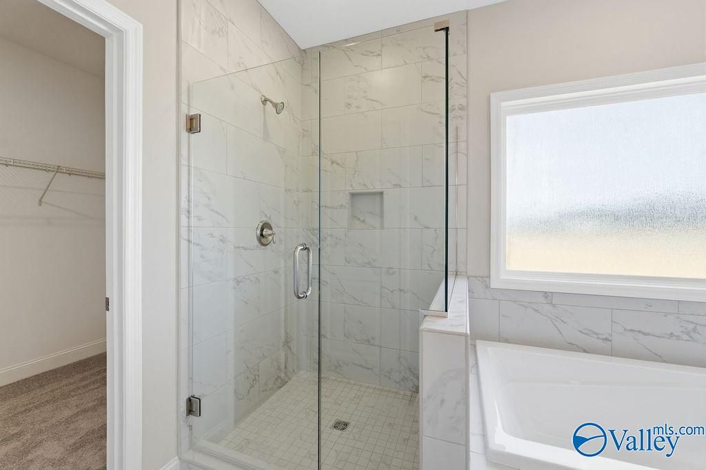 Luxurious master bathroom featuring frameless glass shower, marble tiles, freestanding tub in Davidson Homes The Harrison, Hartselle, AL